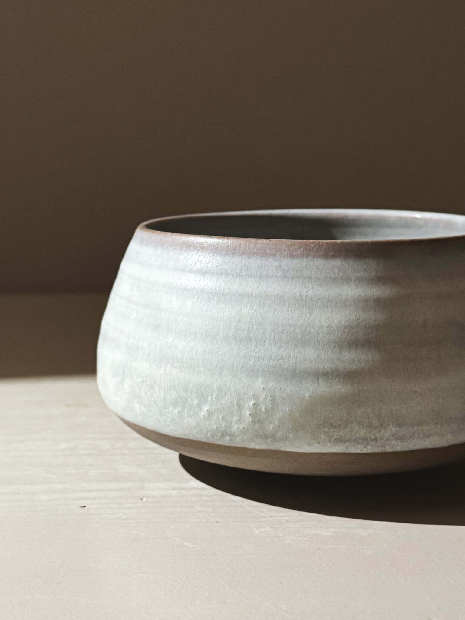 Matcha Bowl - Tsuki #04 made from dark grey stoneware clay with white glaze, showing moonlit tones and hints of blue and grey.