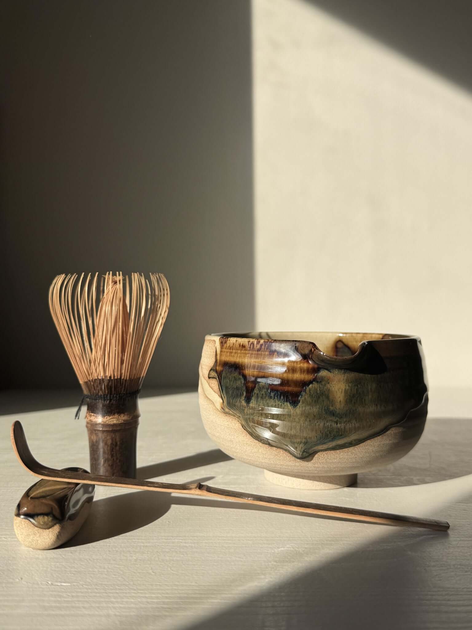 Handmade Matcha Bowl with Spout – Inyo #05 with tenmoku and clear glazes on stoneware, surrounded by traditional matcha tools.