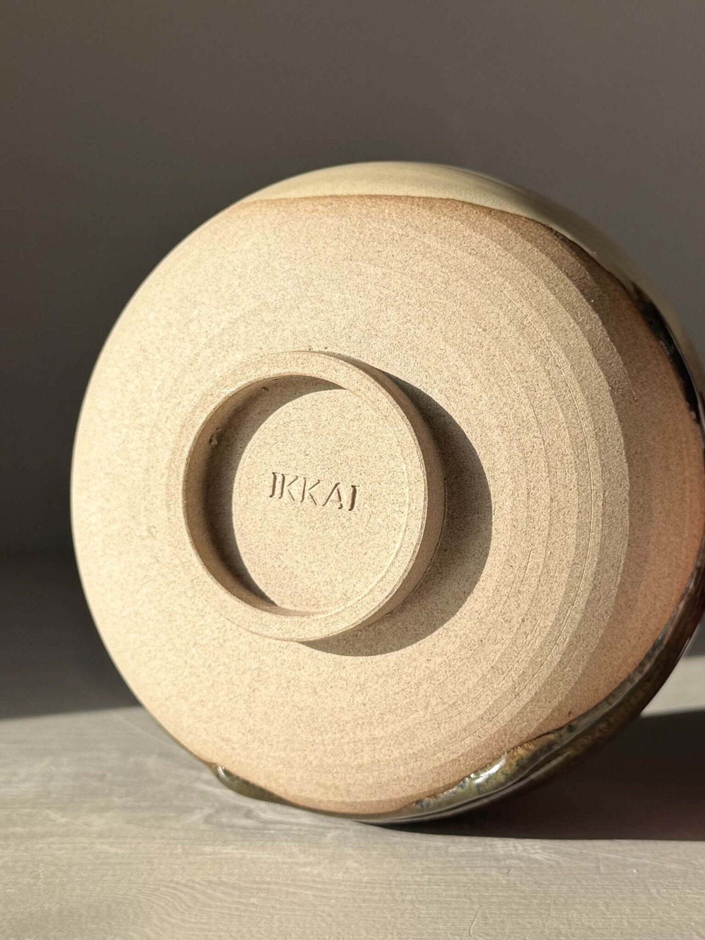 Base of handmade ceramic Matcha Bowl with Spout – Inyo #06 showing warm stoneware clay and unique glaze details.