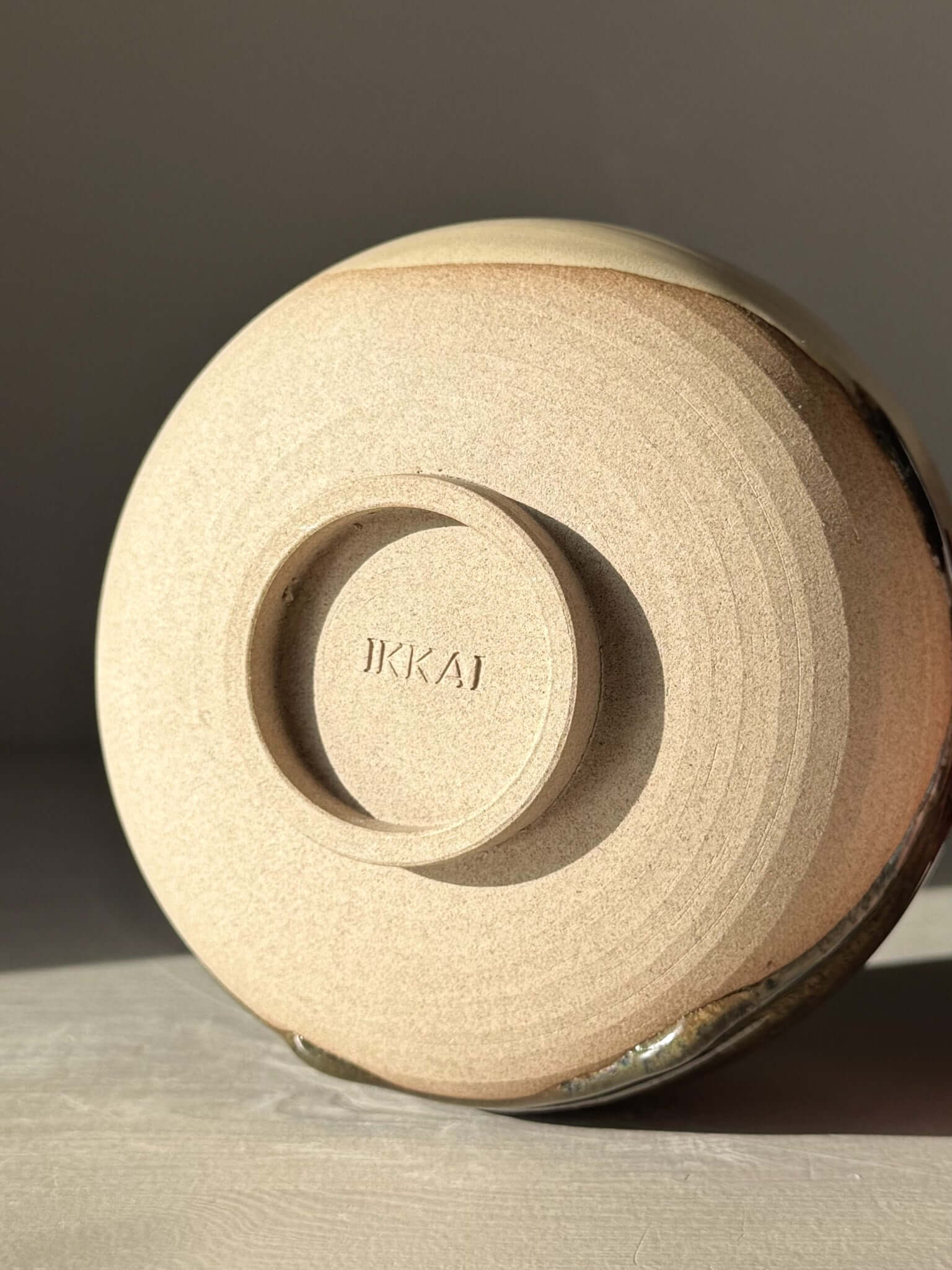 Base of handmade ceramic Matcha Bowl with Spout – Inyo #06 showing warm stoneware clay and unique glaze details.