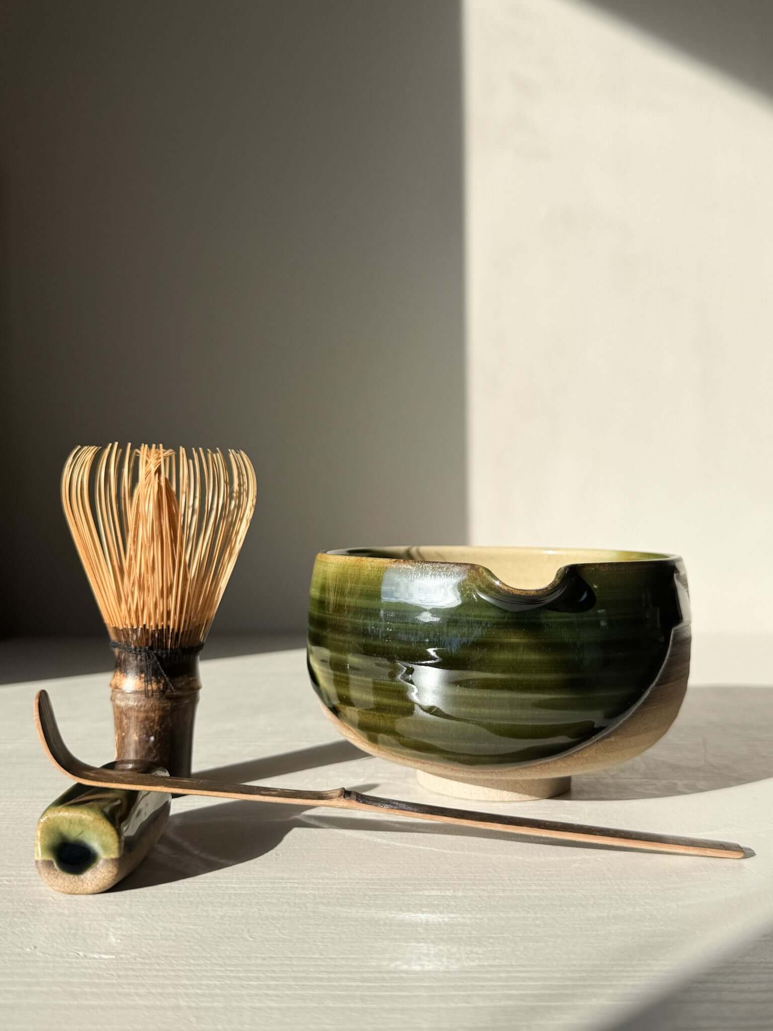 Handmade ceramic Matcha Bowl with Spout – Mori #02 with natural stoneware and green-brown glazes, alongside whisk and tool.