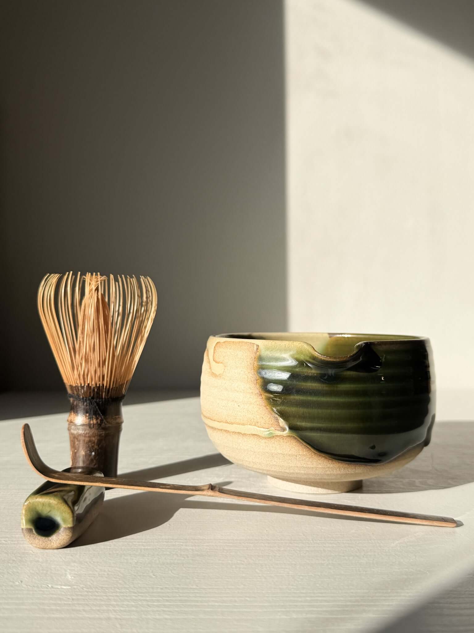 Matcha Bowl with Spout – Mori #03 handmade ceramic with deep green and brown glazes, accompanied by a traditional tea whisk and scoop.