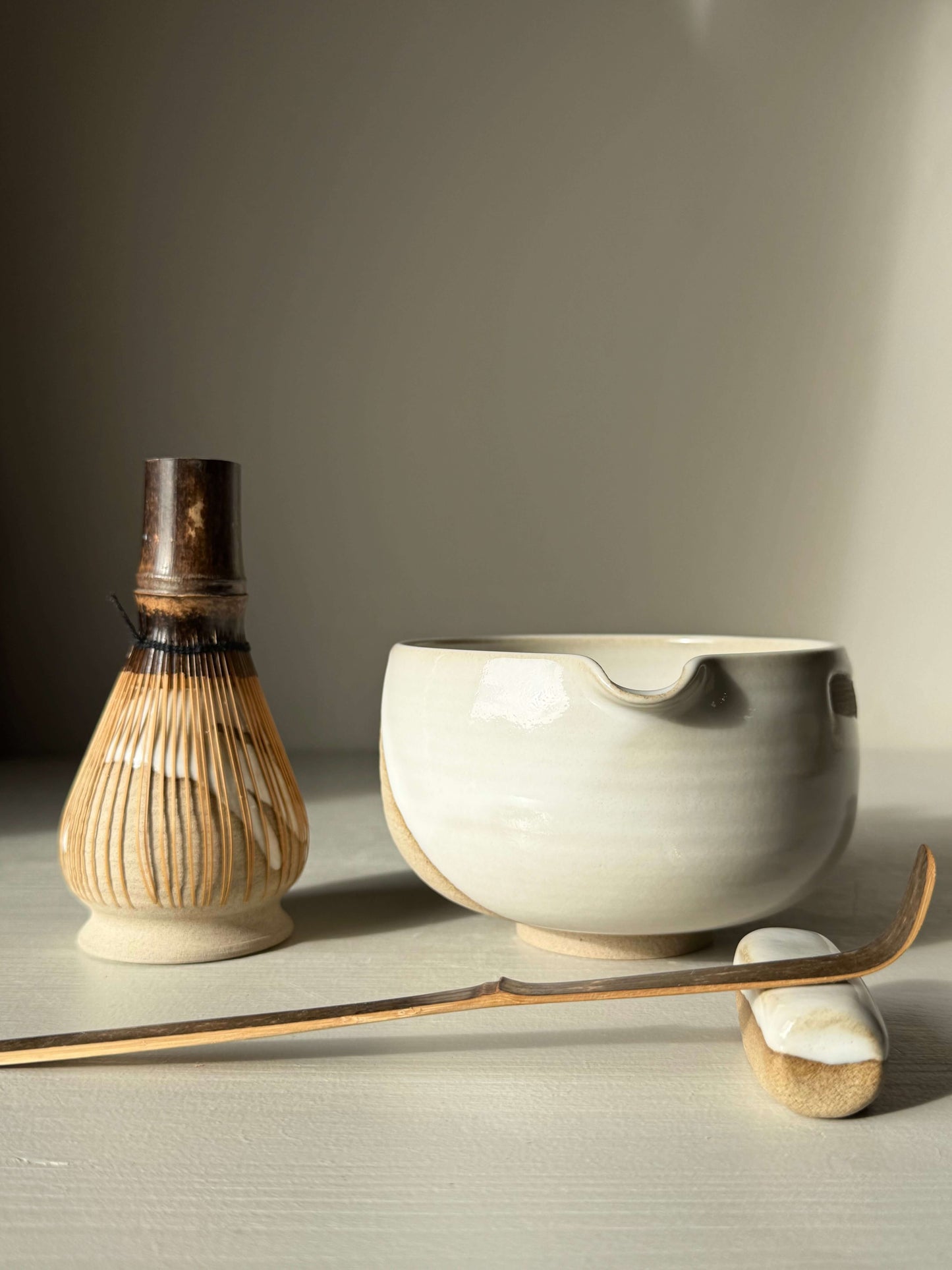 Matcha Bowl with Spout – Yuki #02, handmade ceramic bowl with toffee clay and glossy white glaze, includes bamboo whisk and spoon.