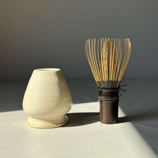 Handmade ceramic Matcha Whisk Holder - Clear Glaze next to bamboo chasen, showcasing elegant curves and transparent glaze finish.