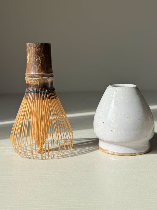 Matcha Whisk Holder - Pale Lilac, handmade ceramic, next to bamboo whisk on a light surface.