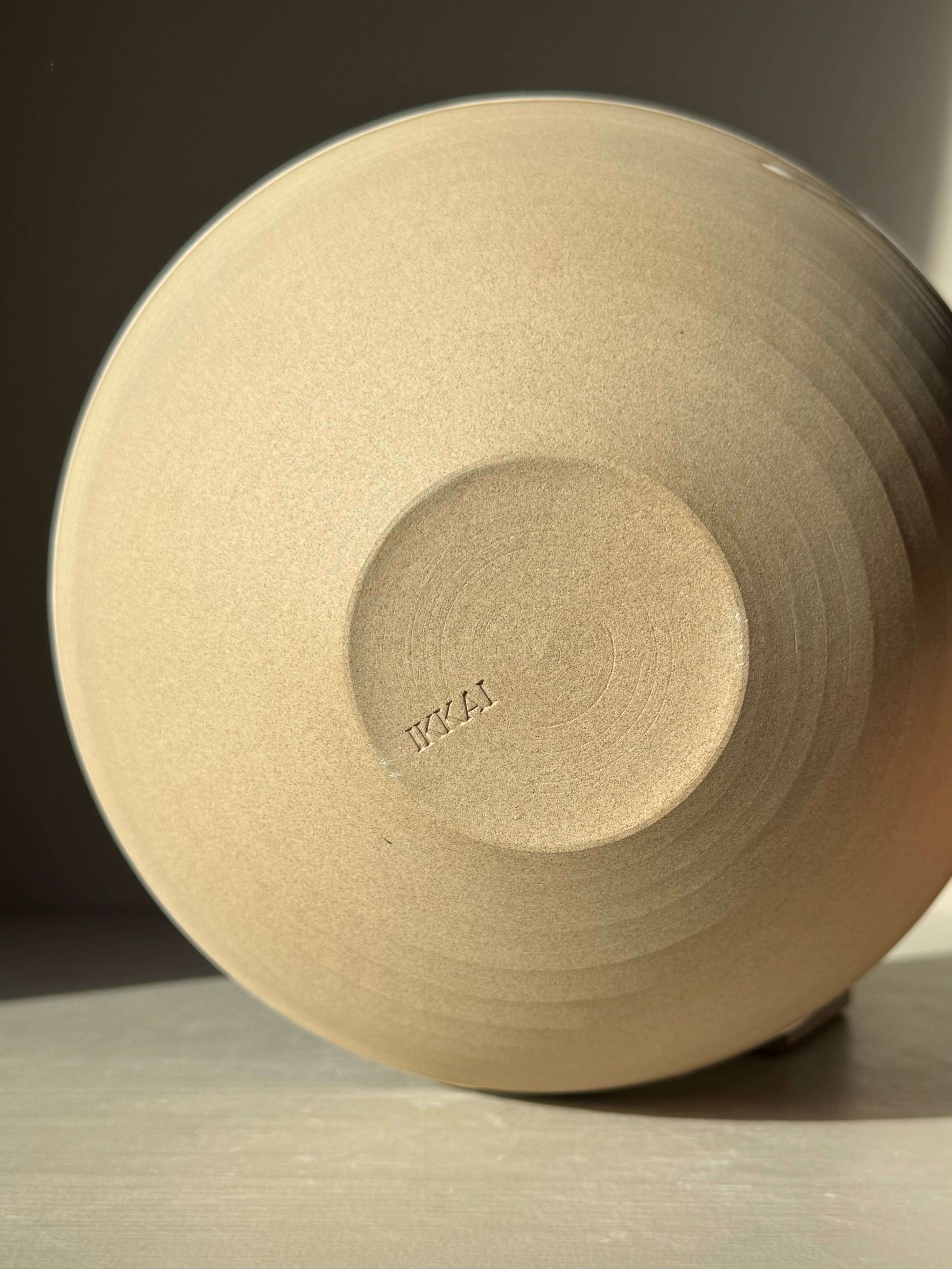 Base of handmade ceramic Medium Bowl - Yuki #02, showcasing raw toffee-colored clay with textured surface.