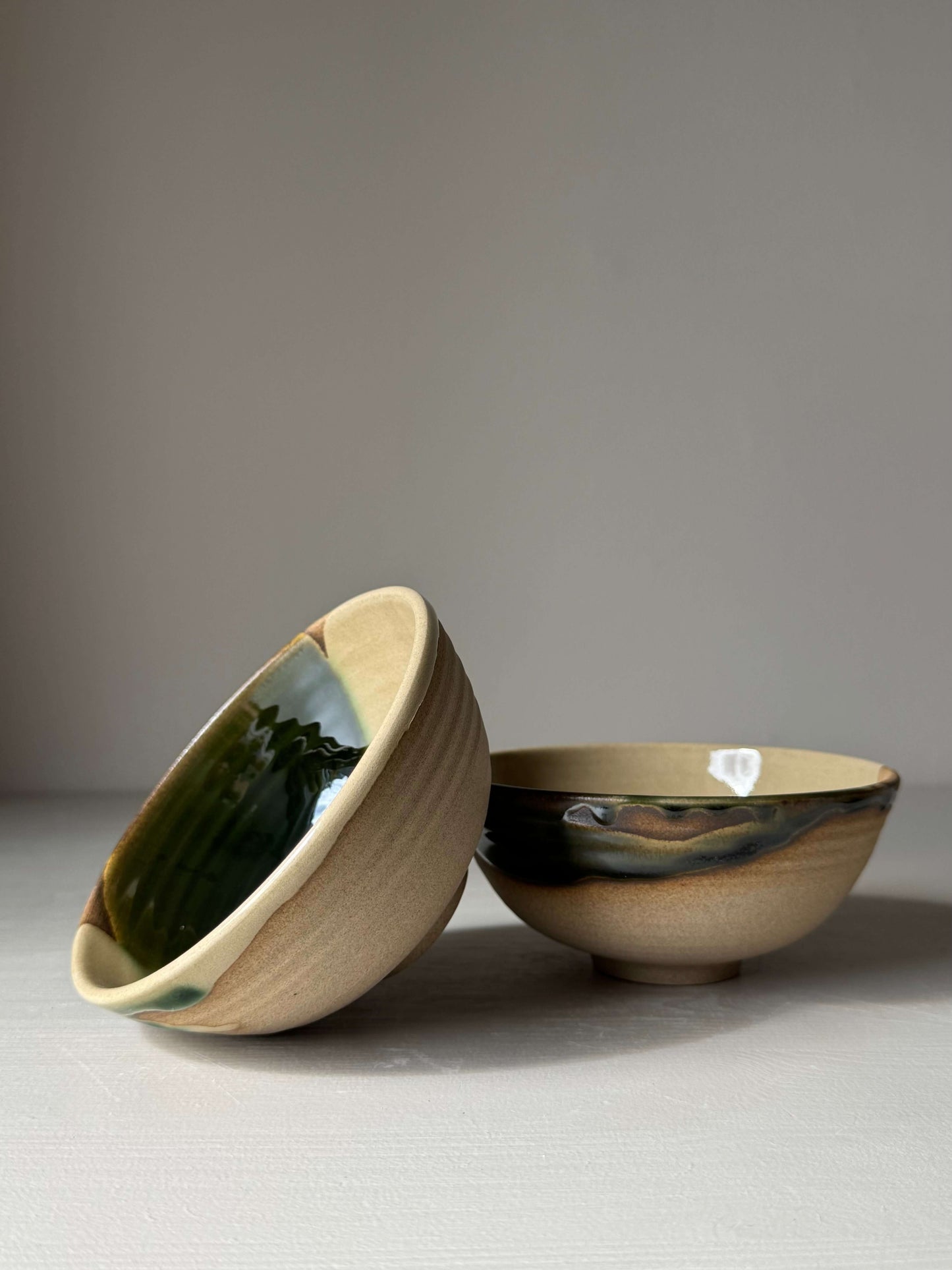 Two handmade ceramic Small Bowl - Mori with green glaze accents on a neutral background.
