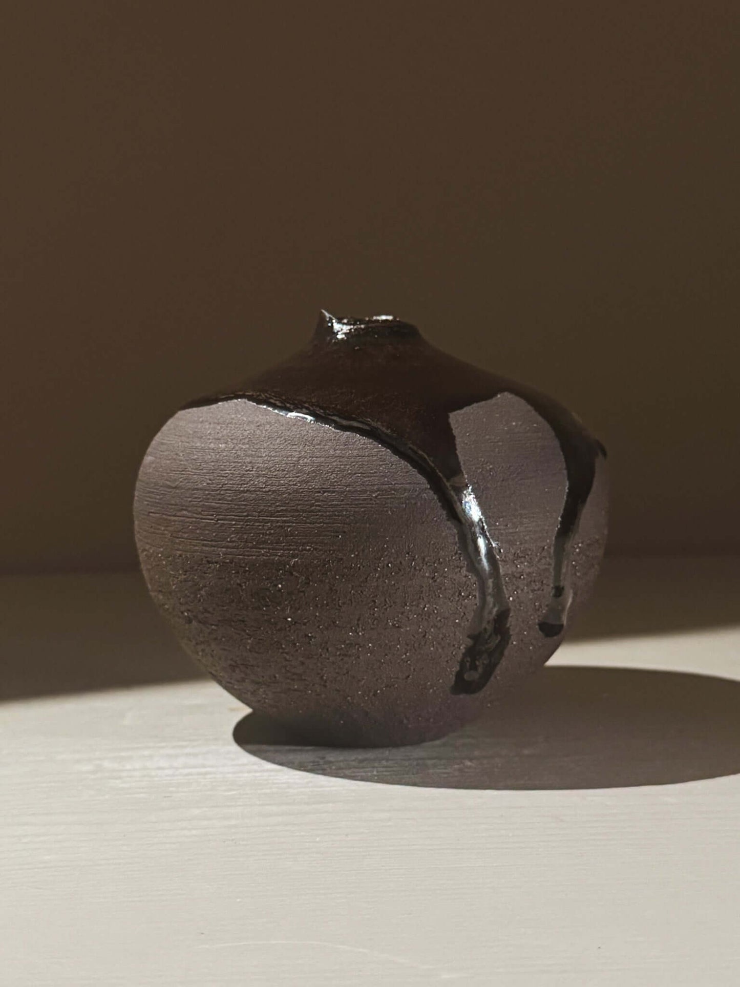 Orb Vase – Kuro Black #02 with unique glaze drips creating organic patterns on a rounded sculptural form.