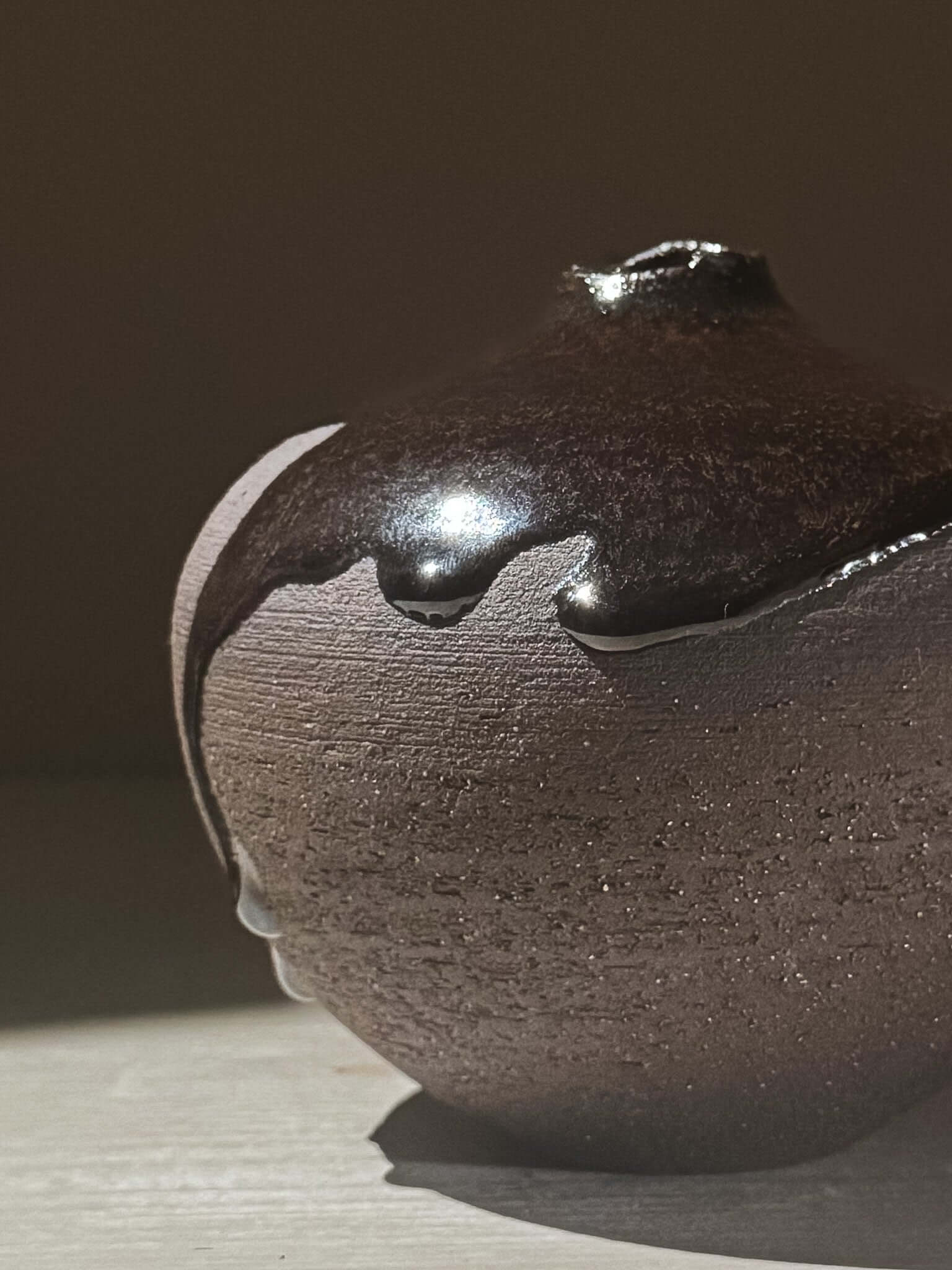 Close-up of Orb Vase – Kuro Black #02 showcasing unique glaze drips on a rounded sculptural form, highlighting its artisanal design.