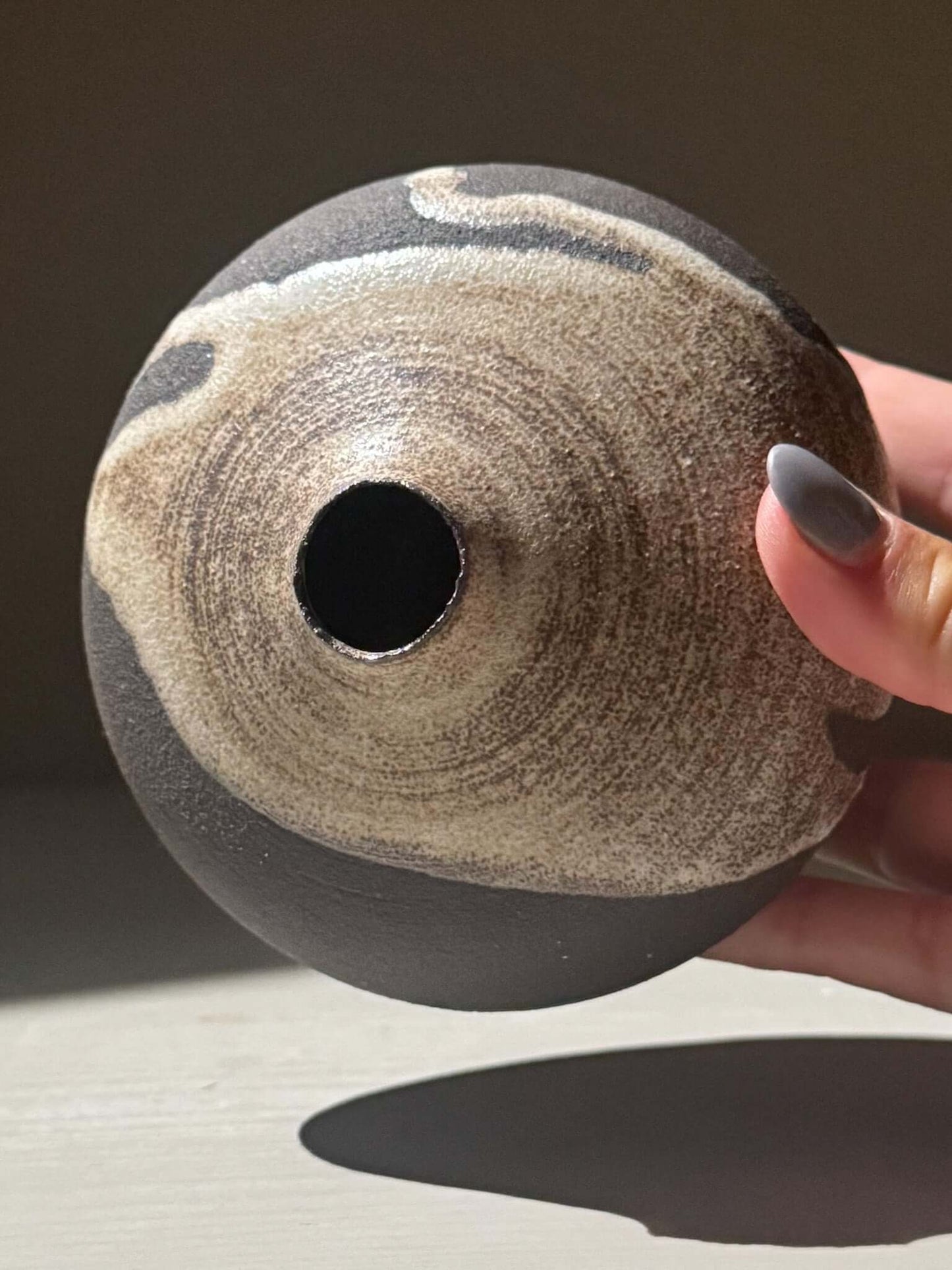 Orb Vase – Matt Clear showing unique glaze patterns and rounded shape, held gently in a hand.