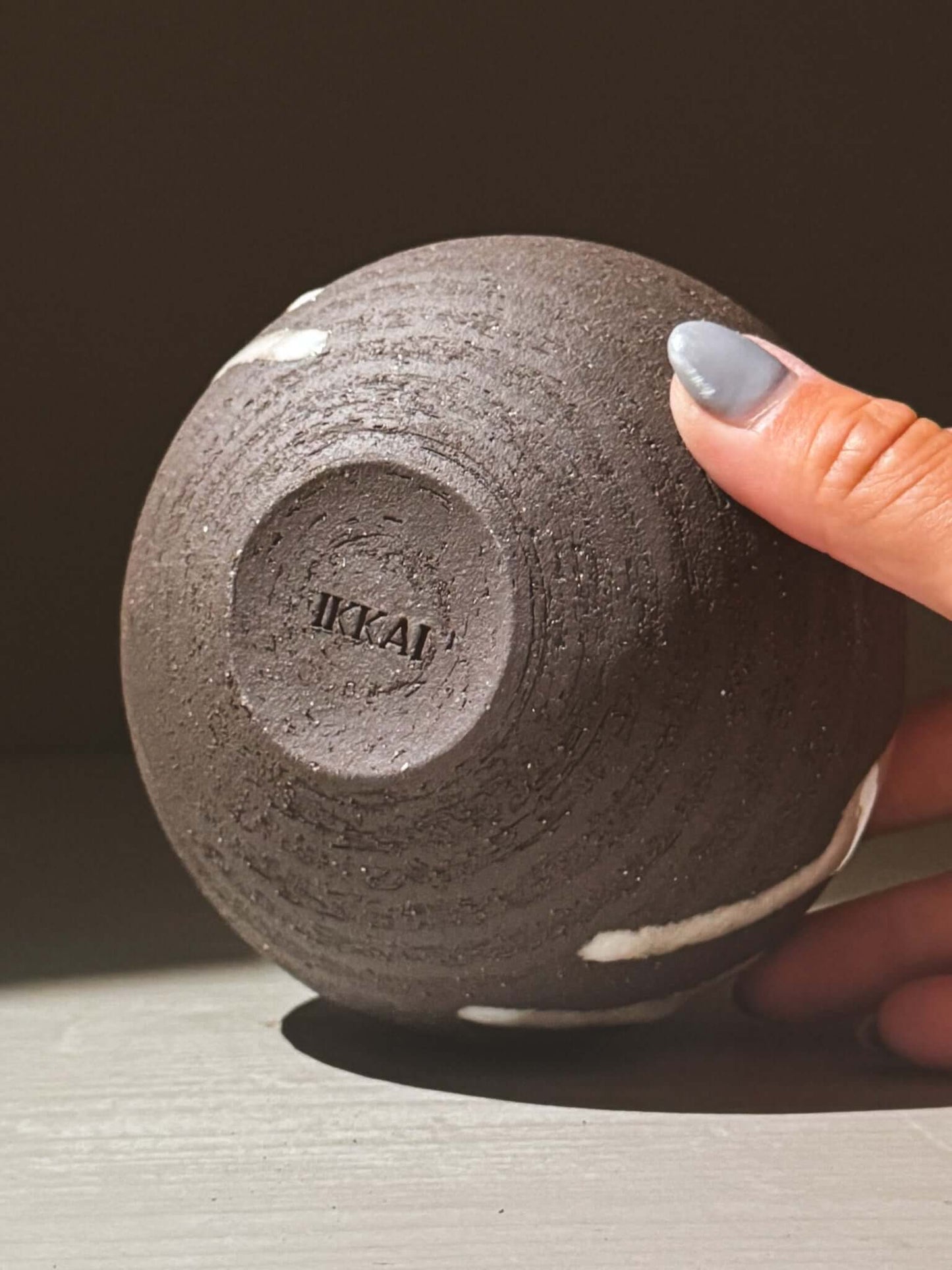 Orb Vase – Yuki Black #09 showing unique glaze patterns and rounded form, held in hand for scale.