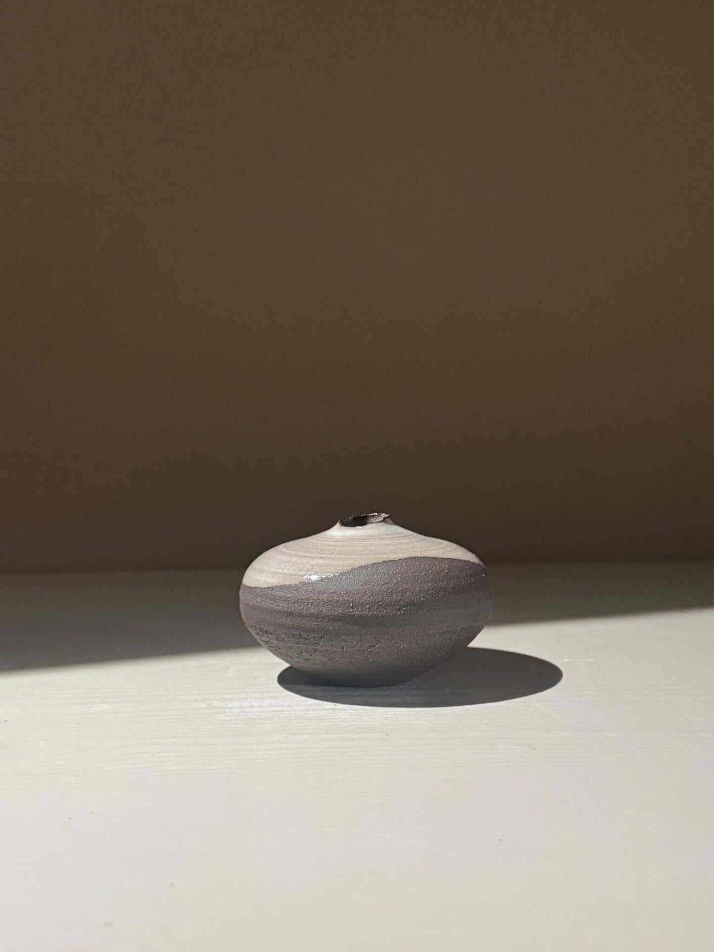 Orb Vase – Yuki Black #13, rounded ceramic vase with unique glaze patterns in natural light.