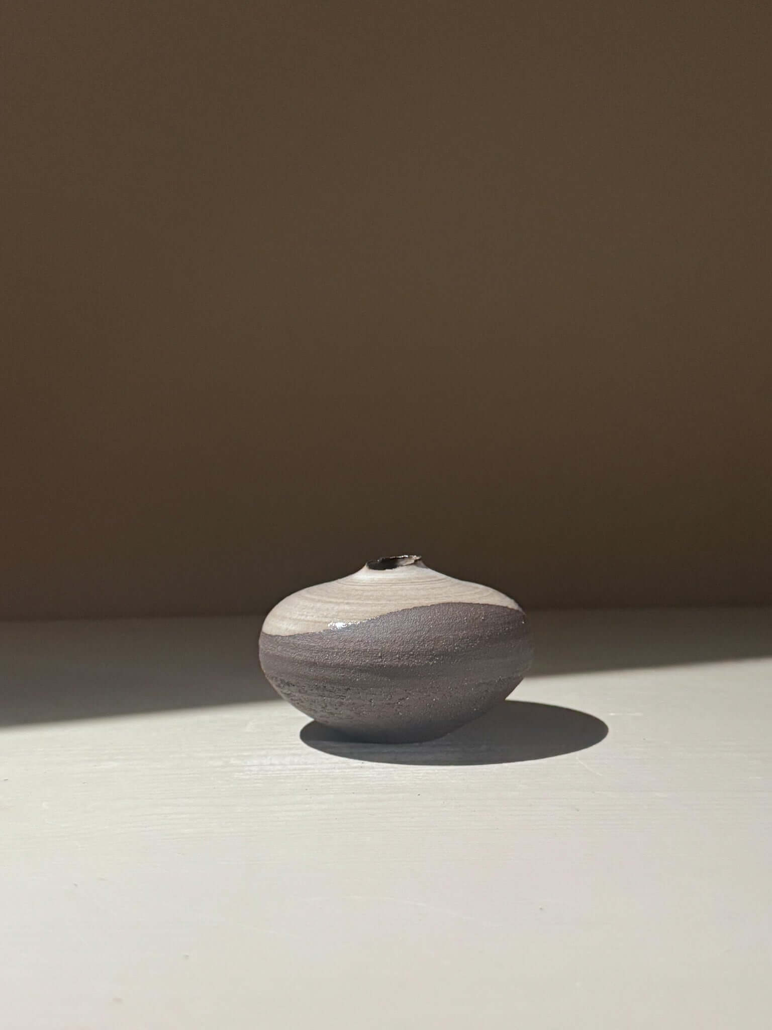 Orb Vase – Yuki Black #13, rounded ceramic vase with unique glaze patterns in natural light.