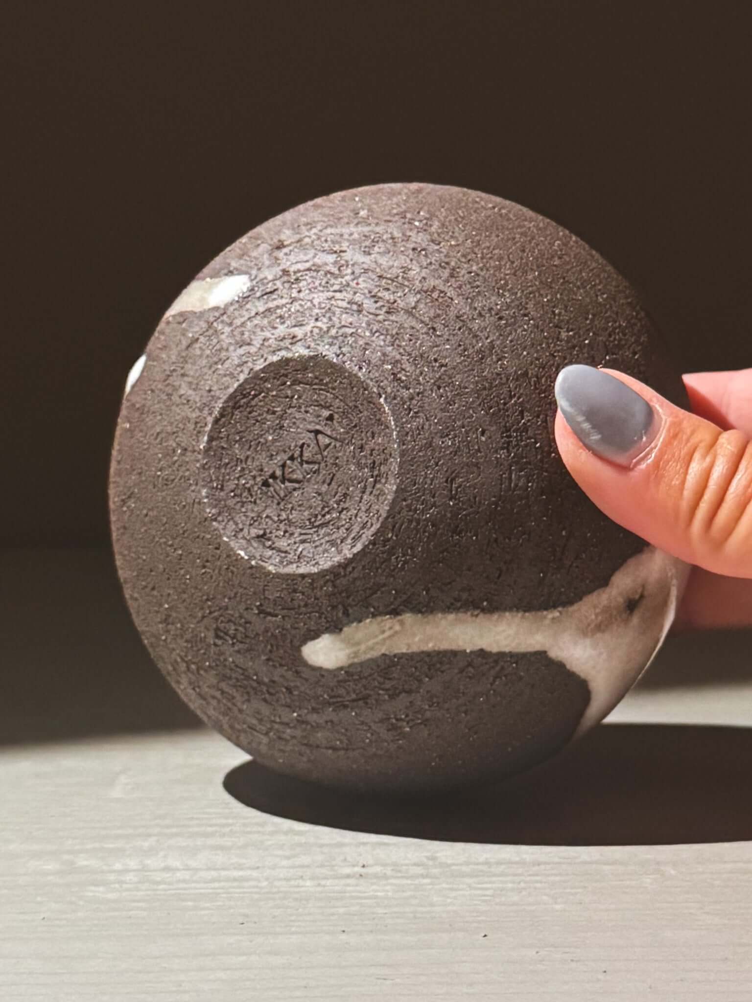 Hand holding Orb Vase – Yuki Black #12 with unique glaze patterns and spherical design