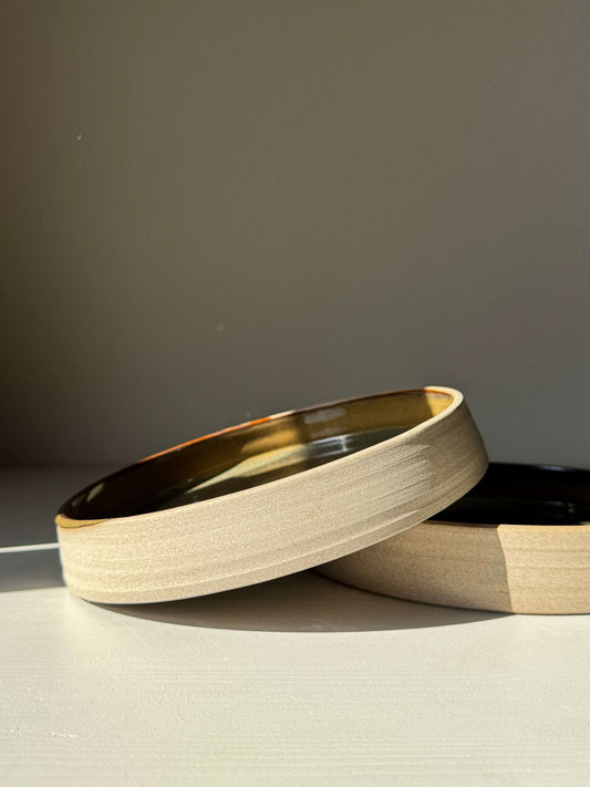 Plate – Inyo Series handmade ceramic plate with glossy tenmoku glaze and raw clay edge, featuring a low, open form with gentle curve.