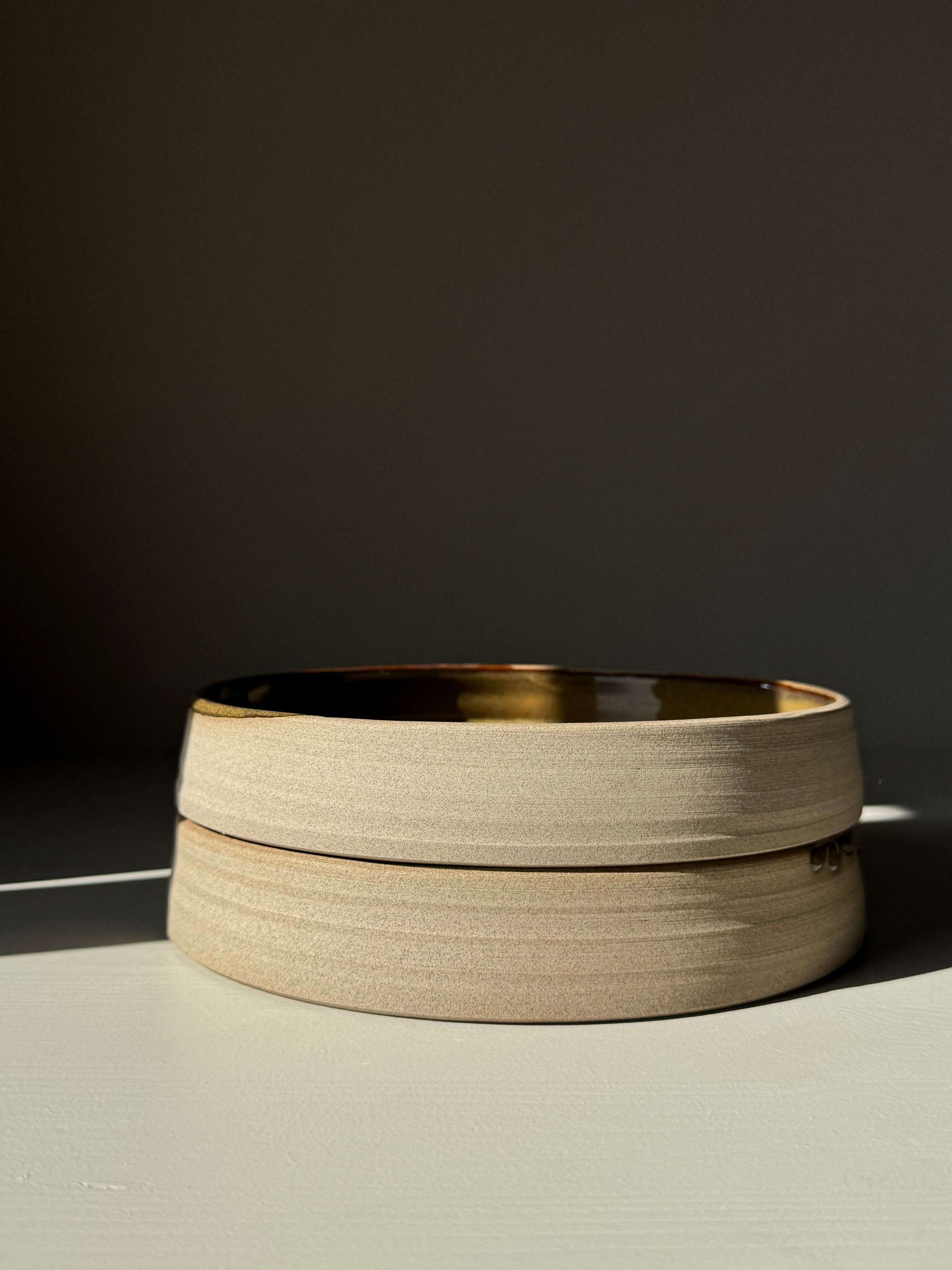 Plate – Inyo Series handmade ceramic plate with glossy tenmoku glaze and raw clay edge, showcasing low, open form with gentle curve.
