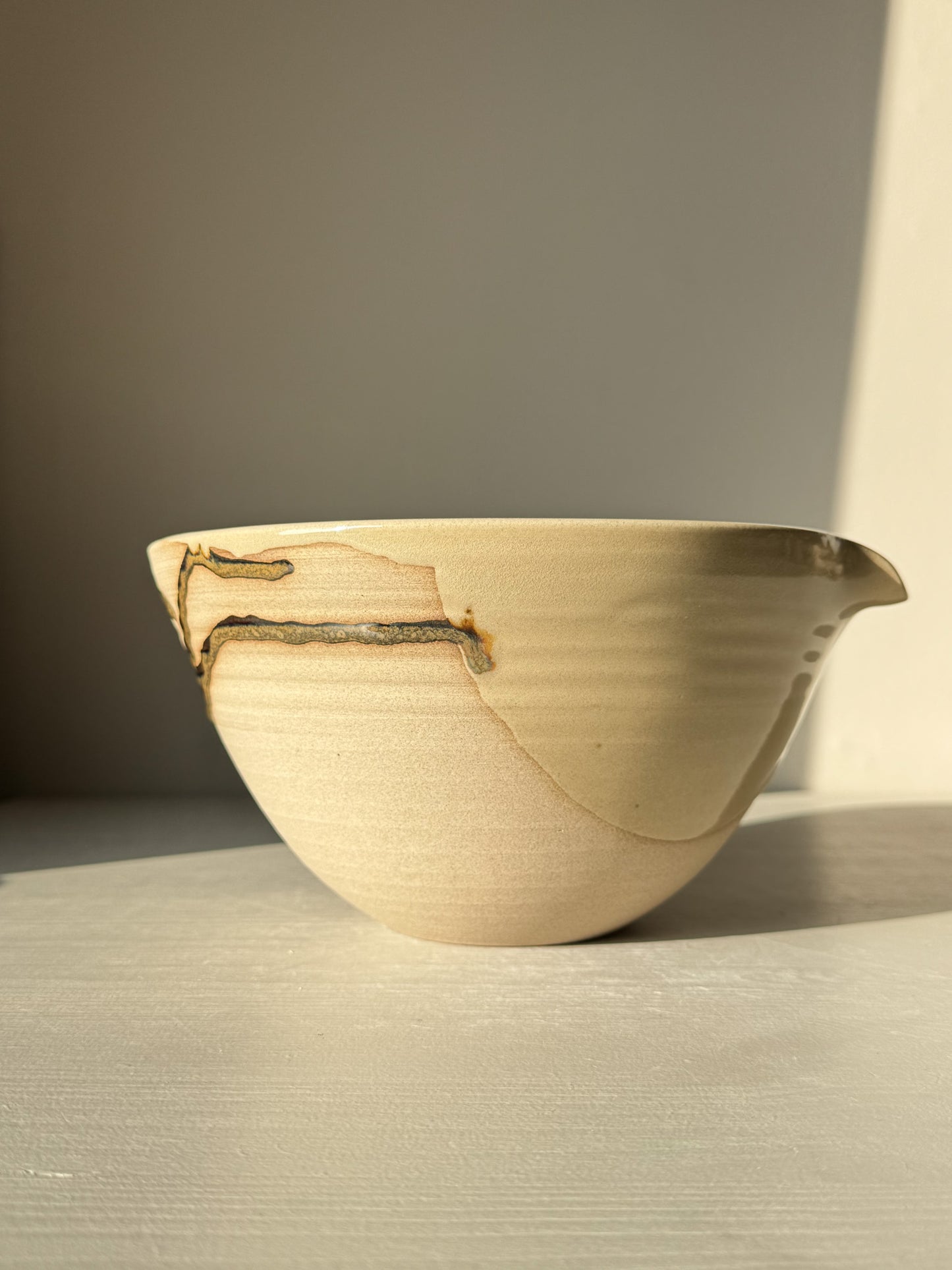Pouring Bowl – Inyo in natural light, showcasing glossy tenmoku and clear glaze over toffee clay with a spout and spiral lines.
