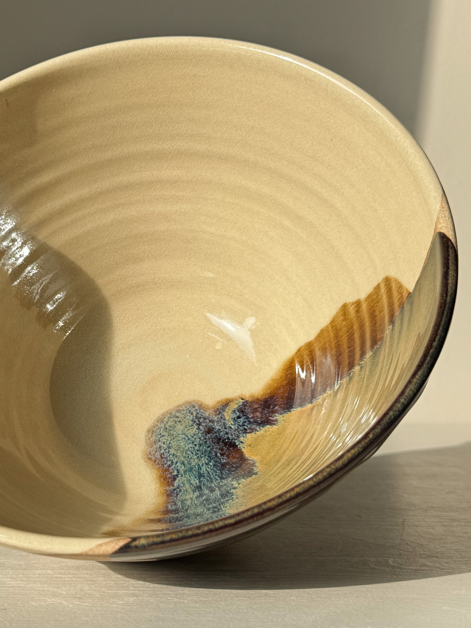 Pouring Bowl – Inyo with glossy tenmoku glaze, clear over toffee clay, showing gentle rim curve and spiraling throwing lines.