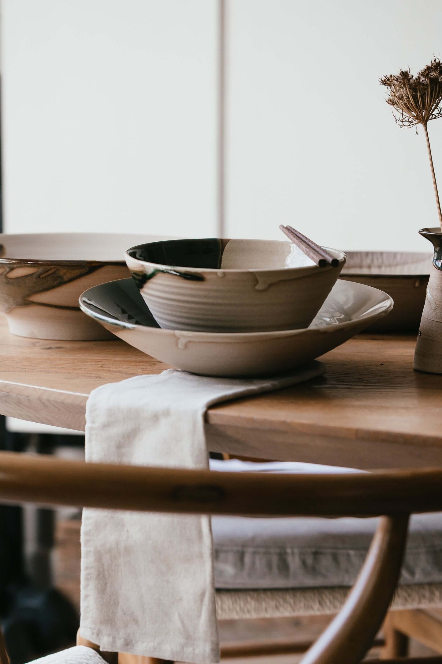 Handmade ceramic Ramen Bowl - Mori Series resting on a wooden table with a green flowing glaze and solid base design.