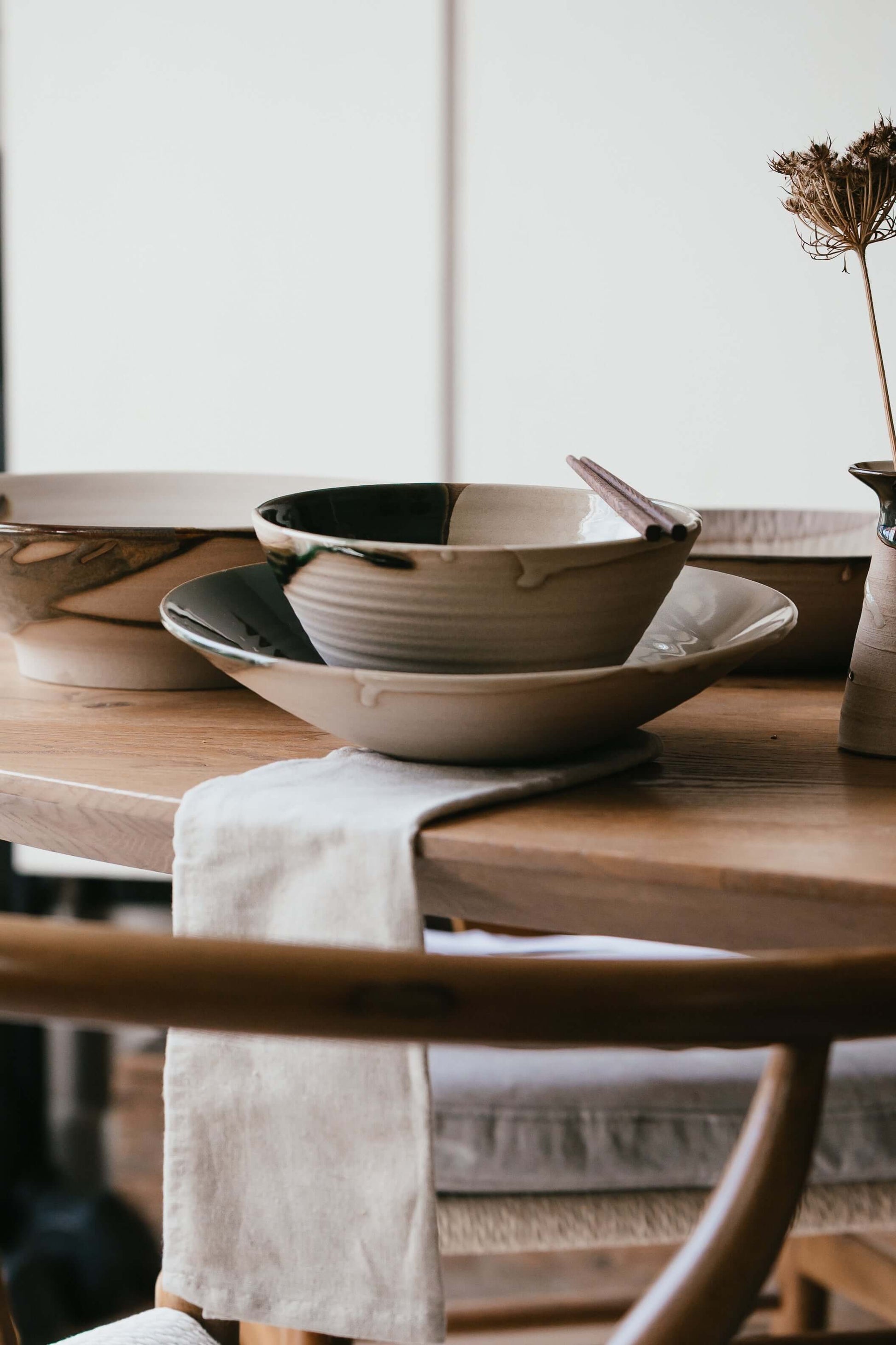 Handmade ceramic Ramen Bowl - Mori Series resting on a wooden table with a green flowing glaze and solid base design.
