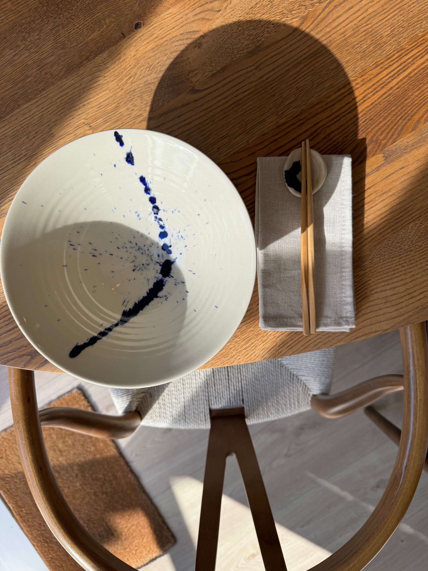 Round Chopstick/Spoon Rest – Gosu with handmade ceramic bowl featuring cobalt blue splashes next to chopsticks on a wooden table.