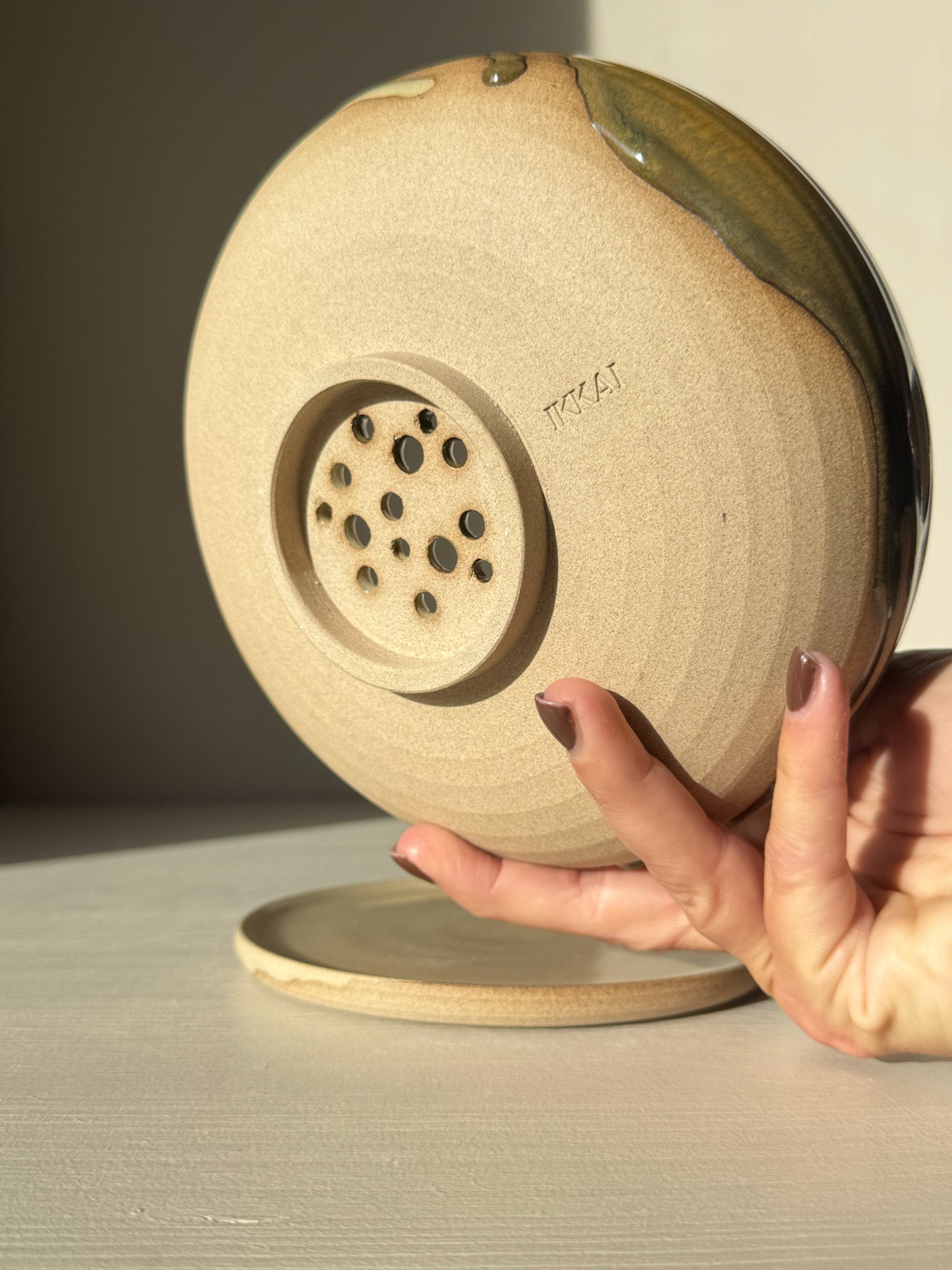 Back view of Rounded Berry Bowl - Inyo #02 with matching drip plate, showcasing its drainage design in soft morning light.