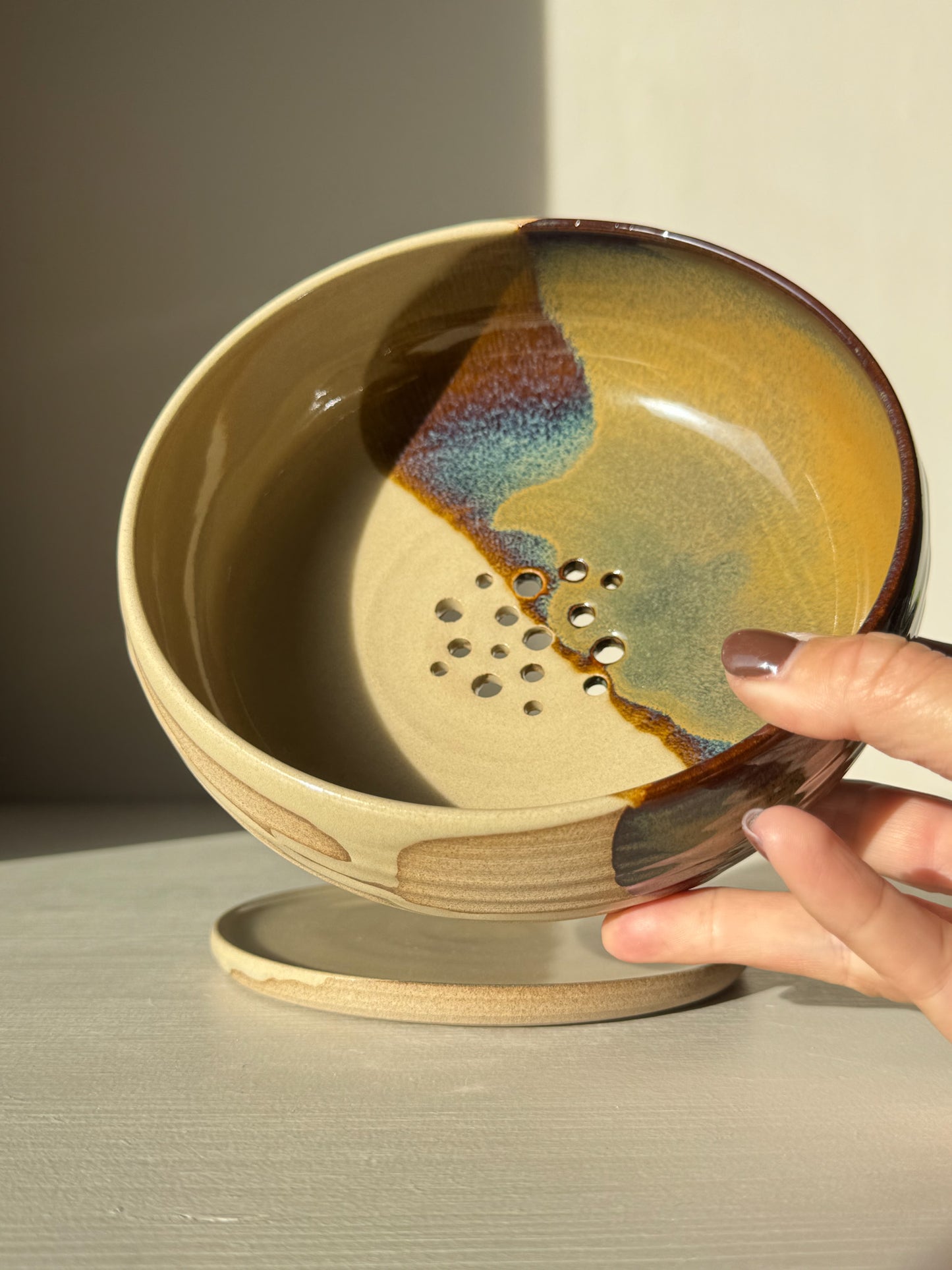 Rounded Berry Bowl - Inyo #01, ceramic bowl with holes and glaze finish, held by hand, ideal for rinsing fruits and herbs.