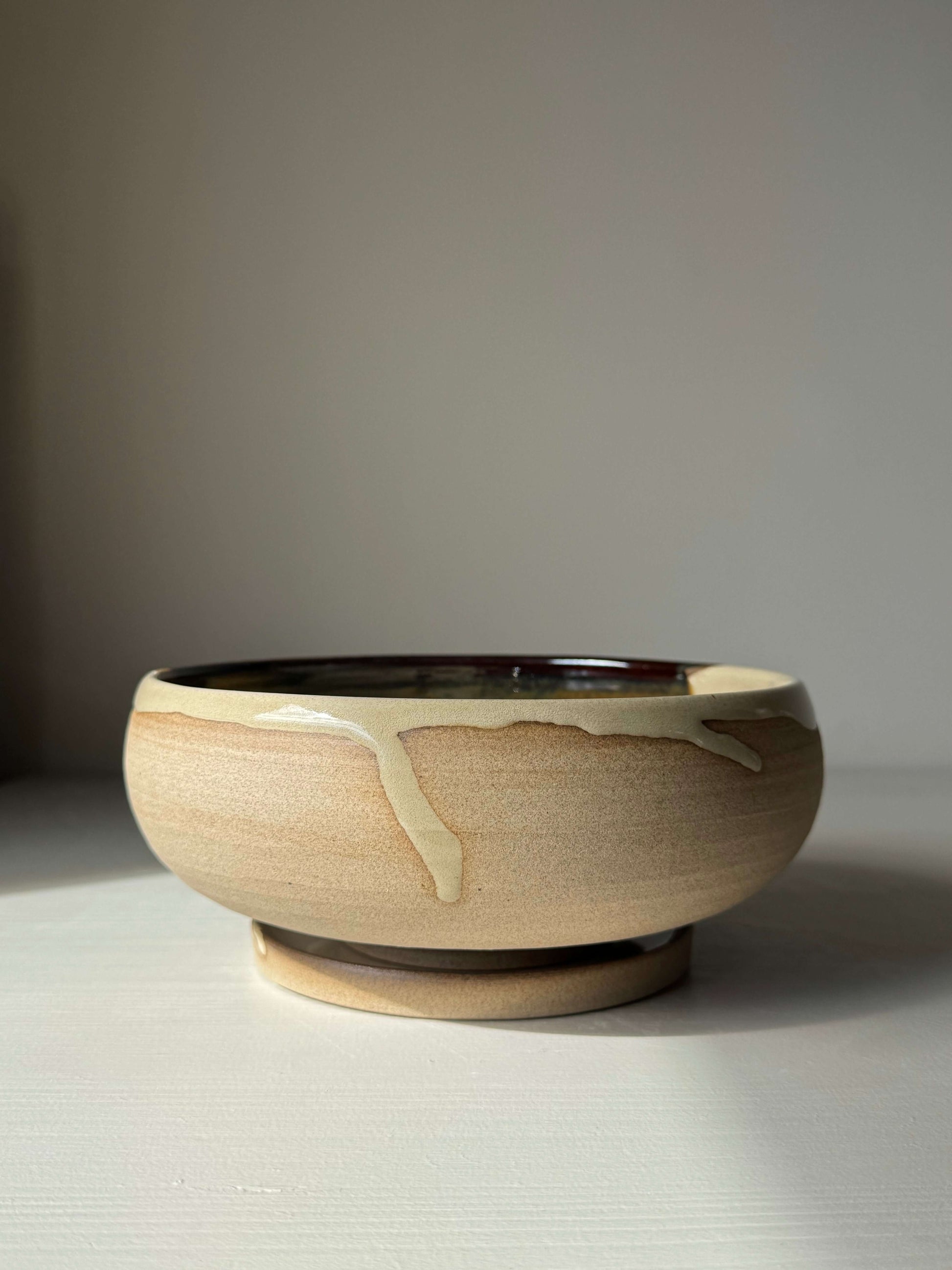 Rounded Berry Bowl - Inyo Series in handmade ceramic with glossy tenmoku glaze on a table.