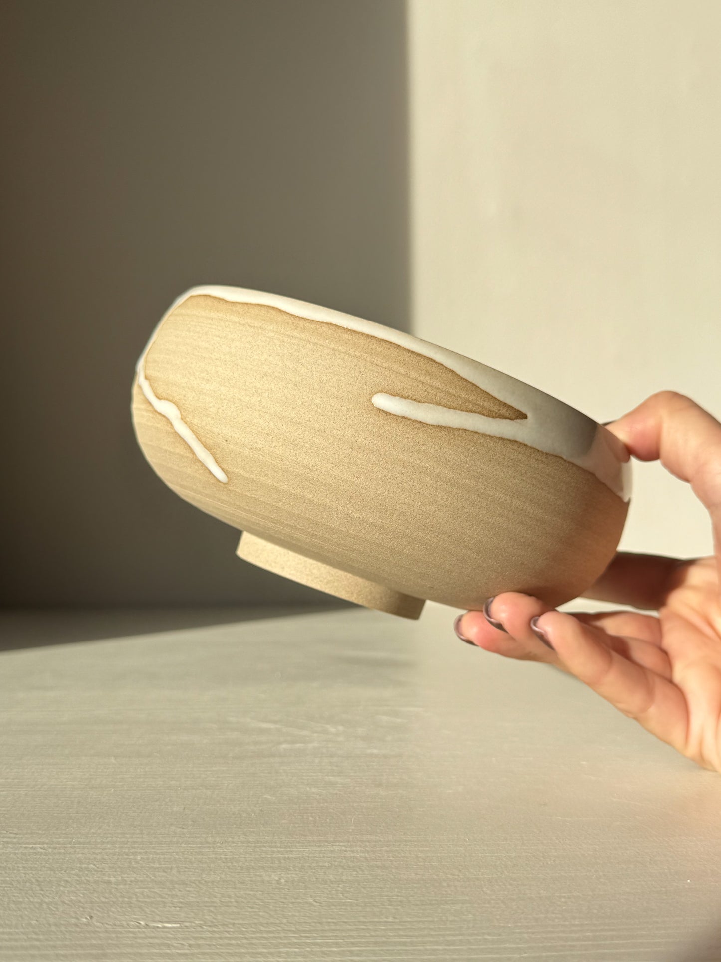 Person holding a Rounded Berry Bowl - Yuki with white glaze over toffee clay, showcasing serene natural contrast.