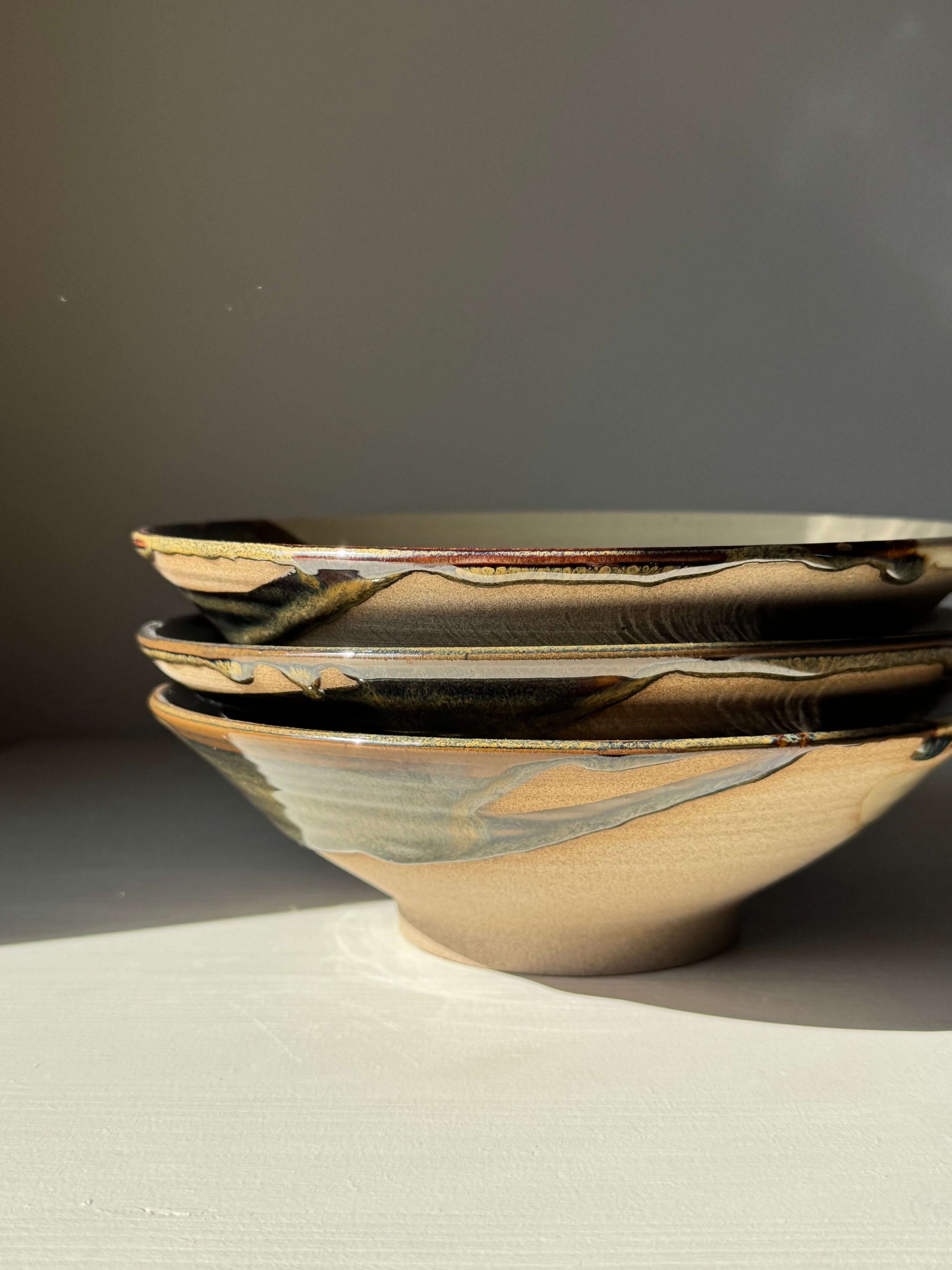 Handmade ceramic Salad/Pasta Plate – Inyo with clear glaze and Tenmoku accents, 23 cm diameter, showcasing light and dark contrast.