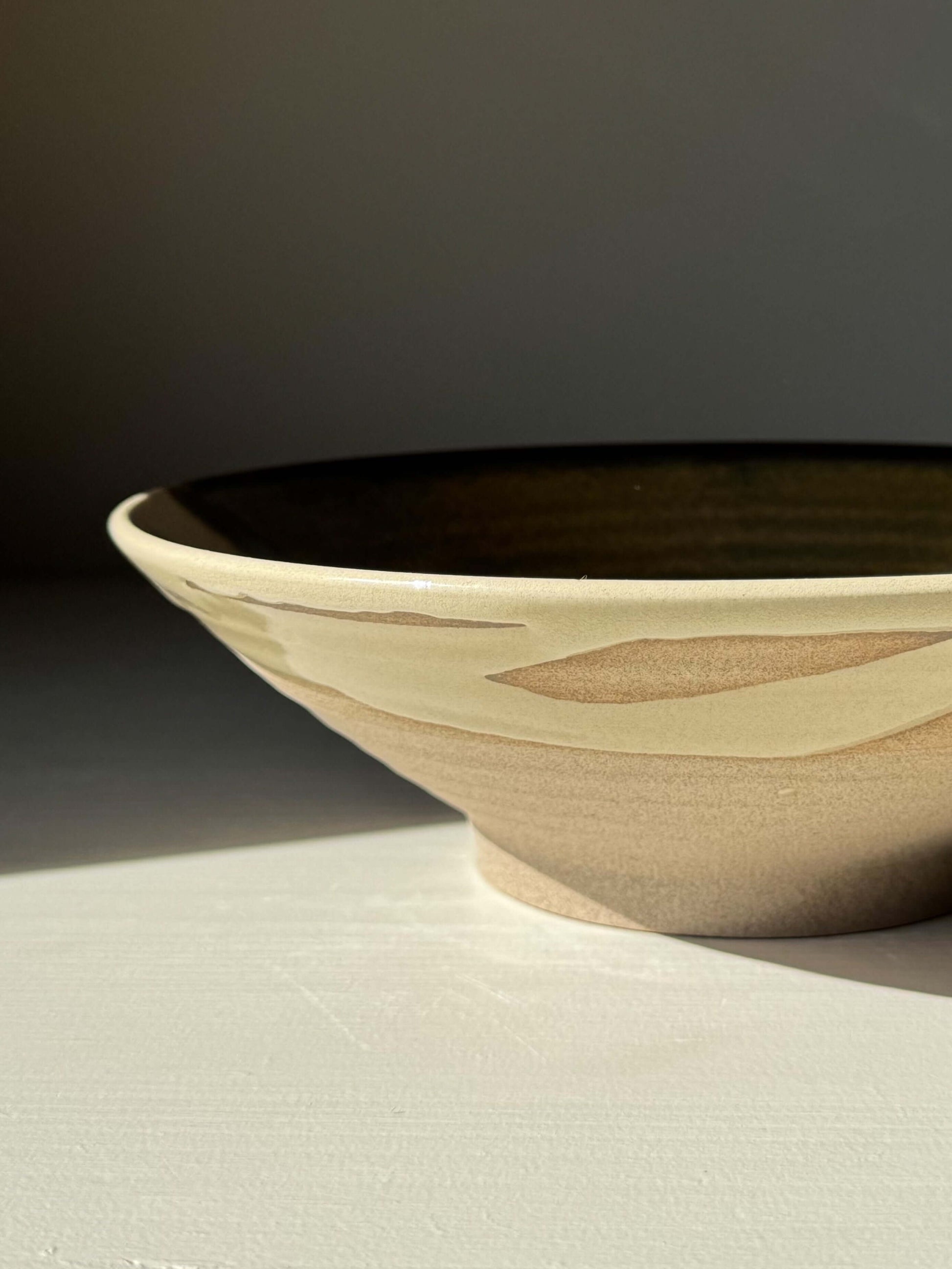Handmade ceramic Salad/Pasta Plate – Inyo with clear glaze and Tenmoku accents, showcasing a contrast of light and dark.