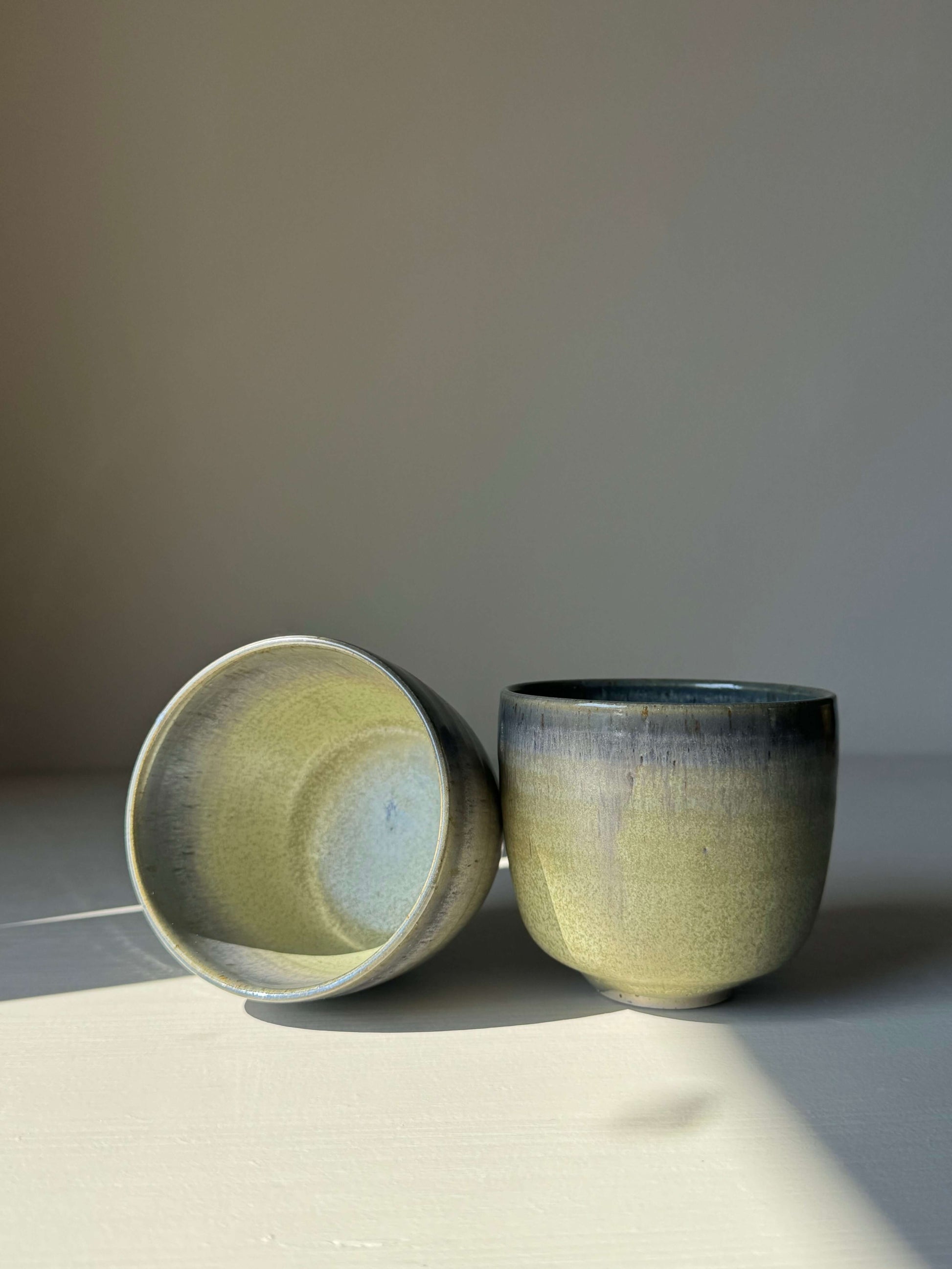 Handmade ceramic Cups - Satin Blue with soft glaze, showcasing misty grey and olive green hues, in rounded, grounding design.