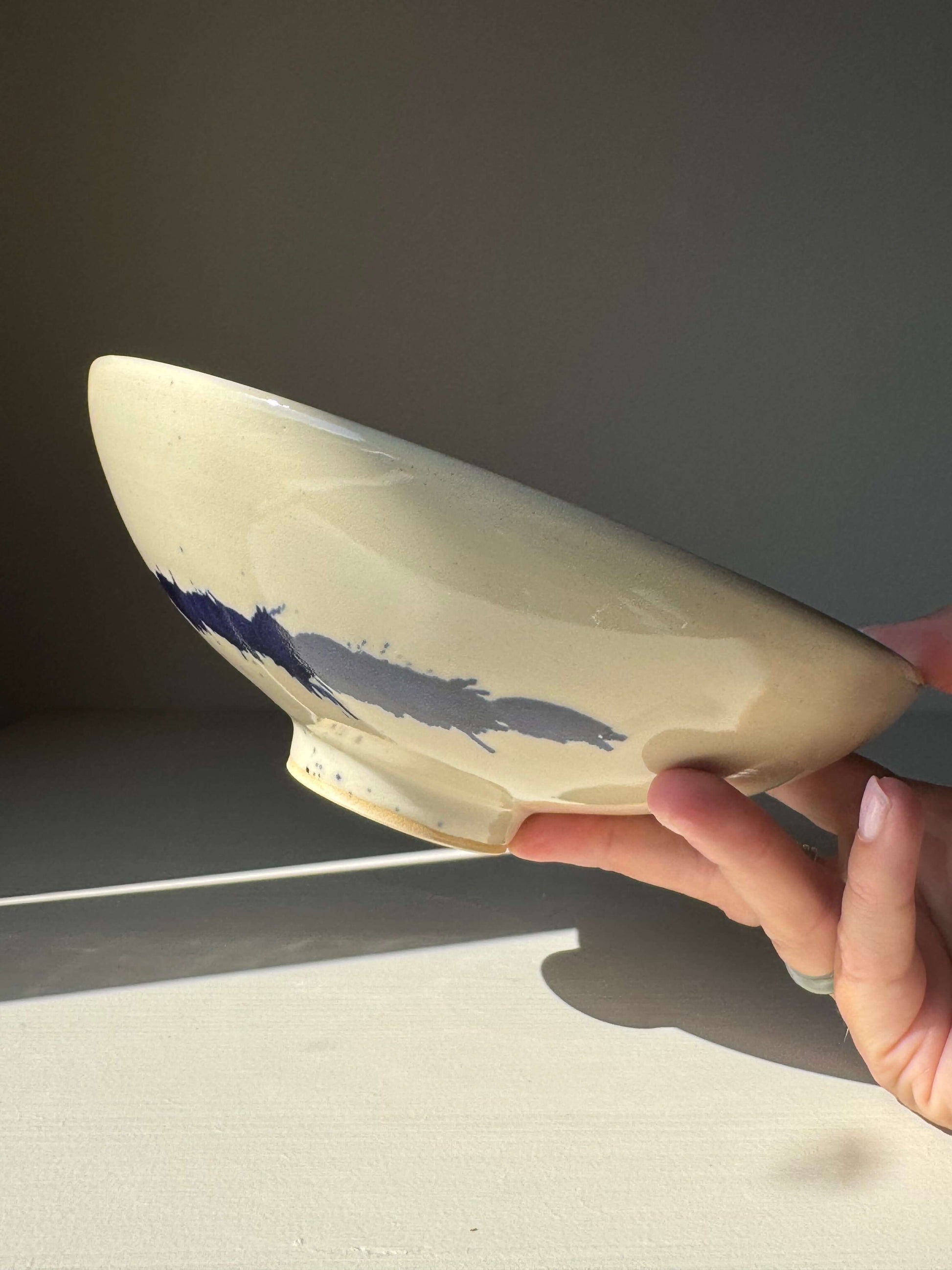 Shallow Dish - Gosu Series handmade ceramic with cobalt splashes in hand, highlighting its raised foot and durable stoneware material.