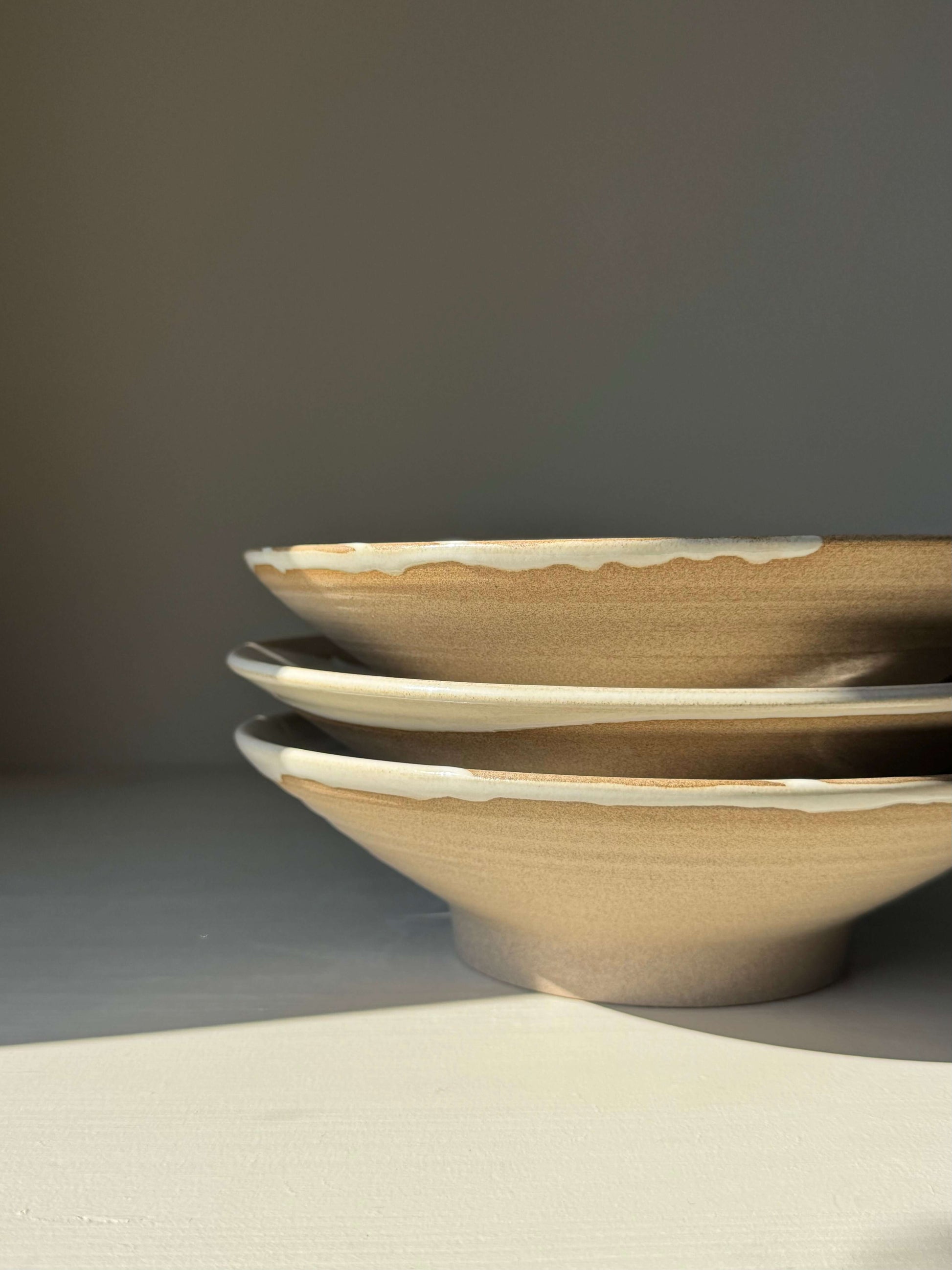 Stack of handmade ceramic Shallow Plate – Yuki with raw clay exterior and glossy white glaze, approx. 23 cm diameter.