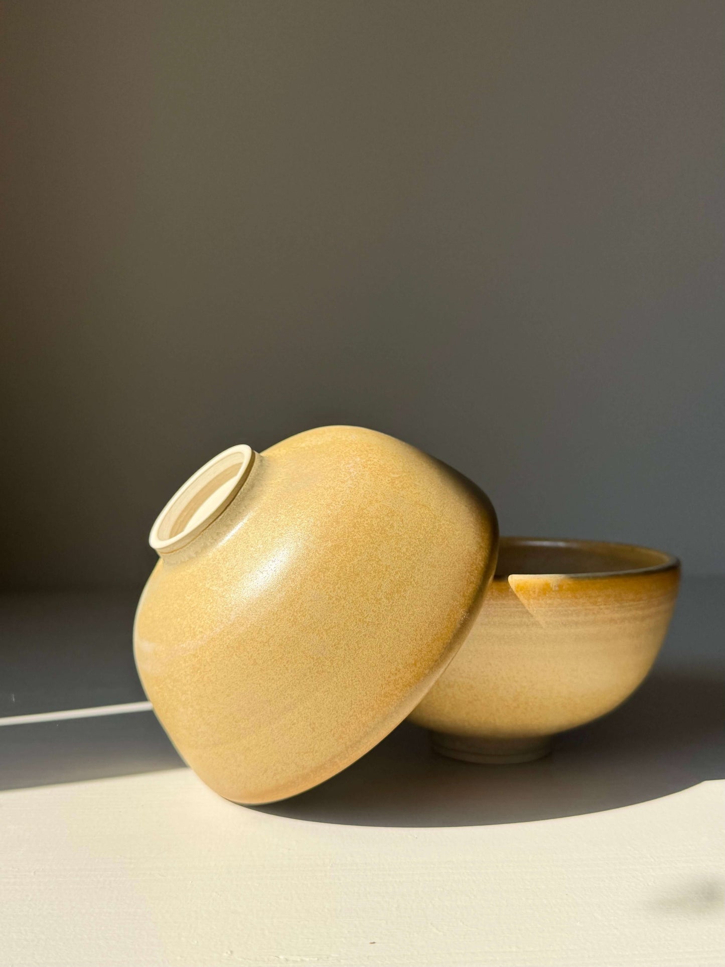 Small Bowl - Golden Yellow handmade ceramic with ochre to honey glaze, showing subtle speckles and swirls, two bowls on display
