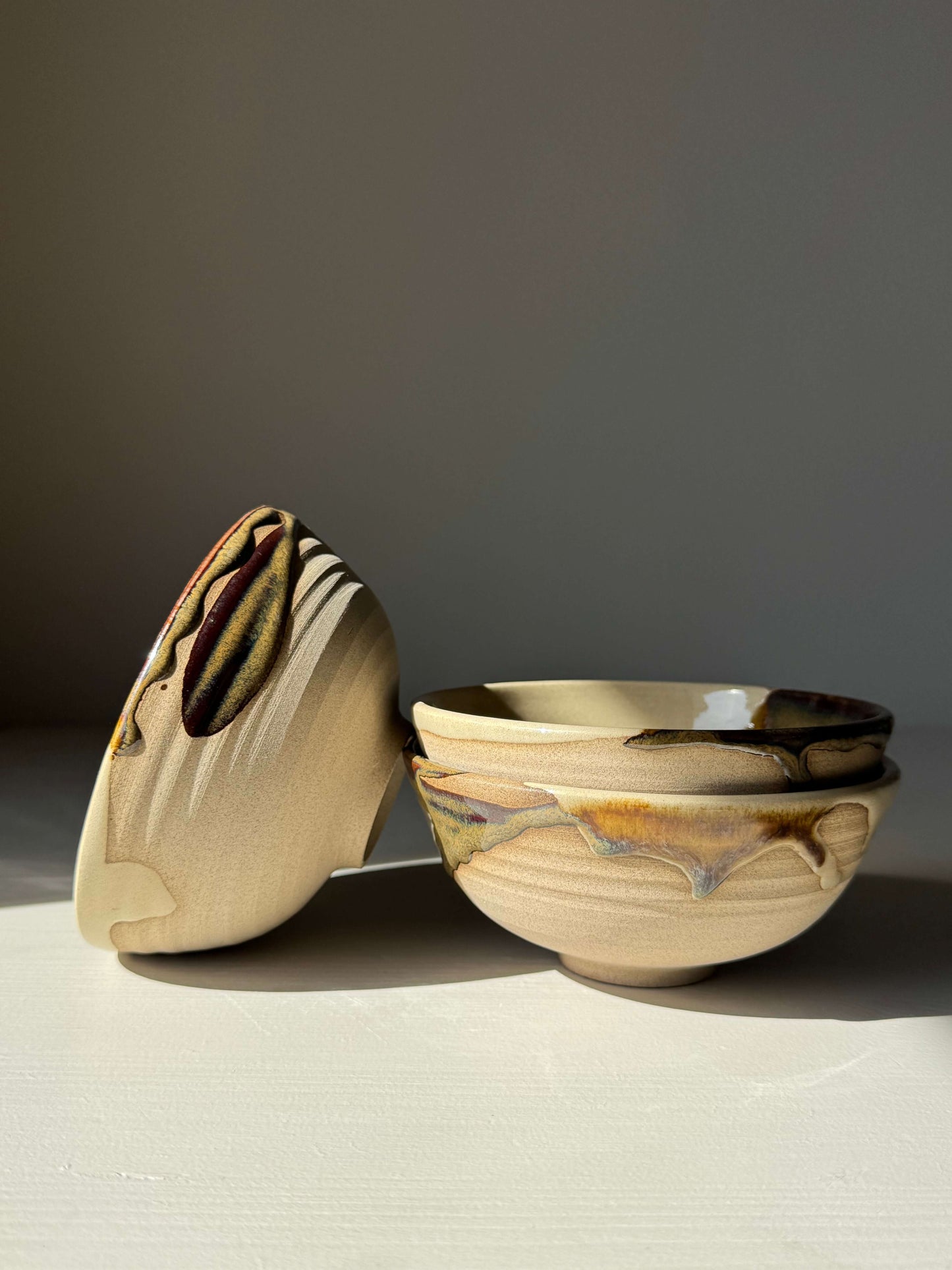 Handmade ceramic Small Bowl - Inyo with tenmoku glaze, showcasing duality of raw stoneware and flowing colors of black, bronze, and cream.