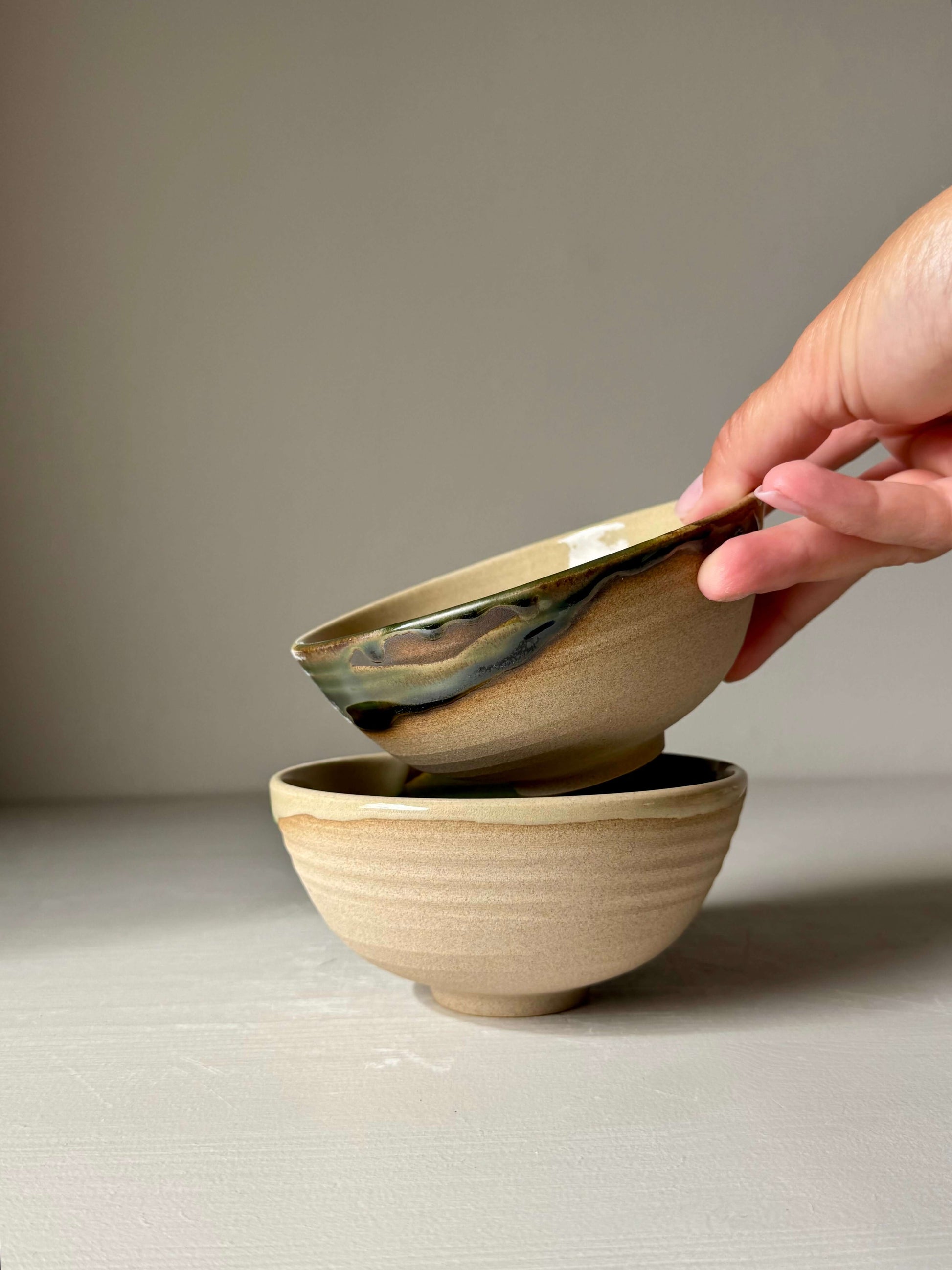 Hand holding Small Bowl - Mori from the Mori Series, a handmade ceramic with flowing green glaze over stoneware, inspired by forest serenity.