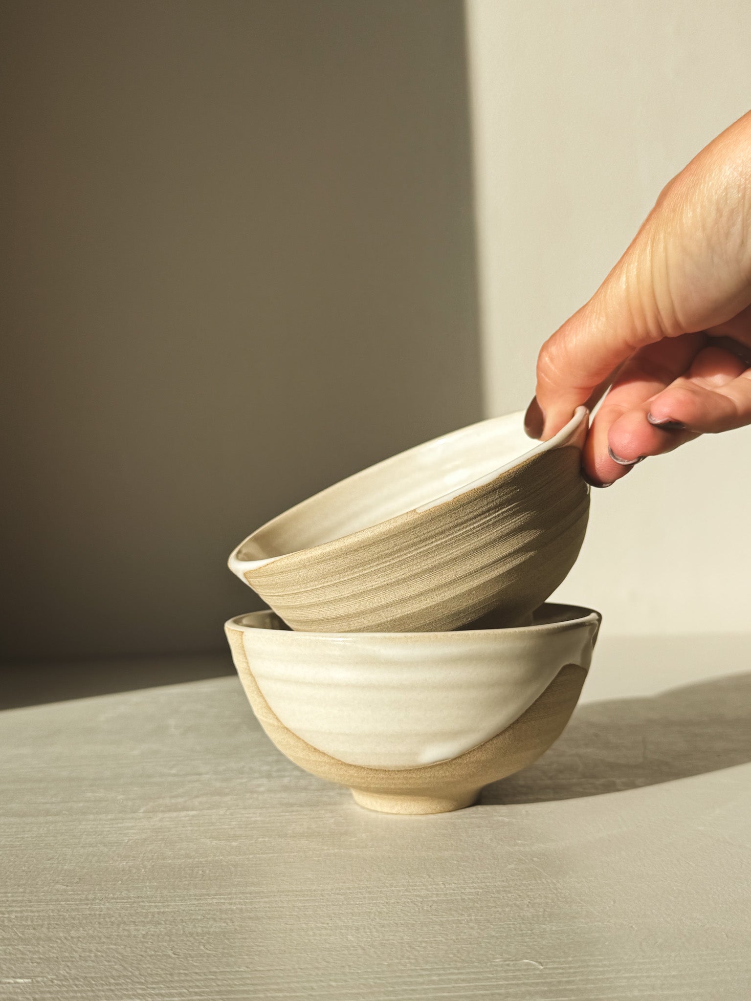Hand holding stack of two Small Bowl - Yuki with white glaze and warm clay texture