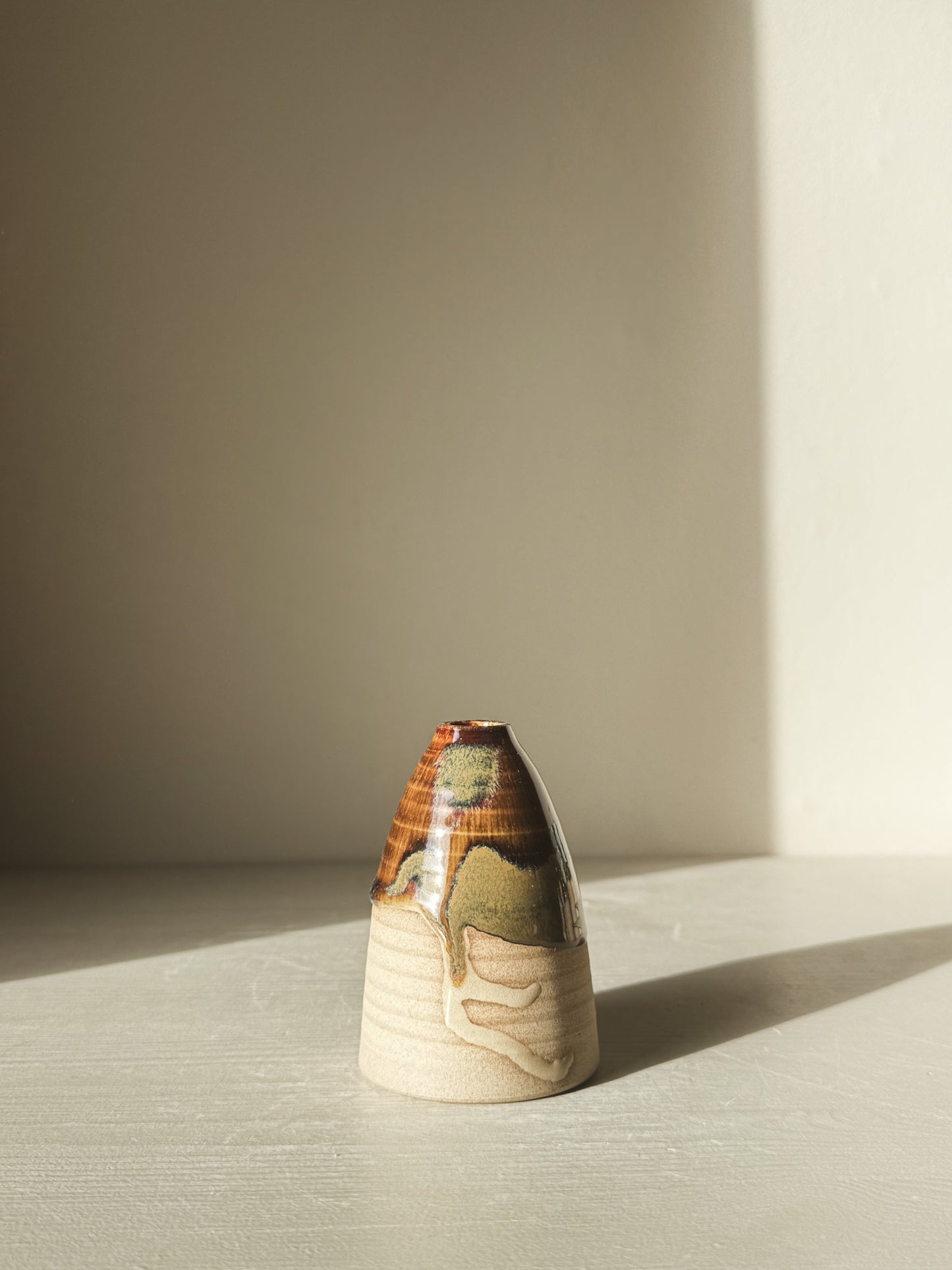 Small Vase – Inyo #02 with glossy tenmoku glaze and raw clay texture, displaying gentle curves and earthy tones in natural light.