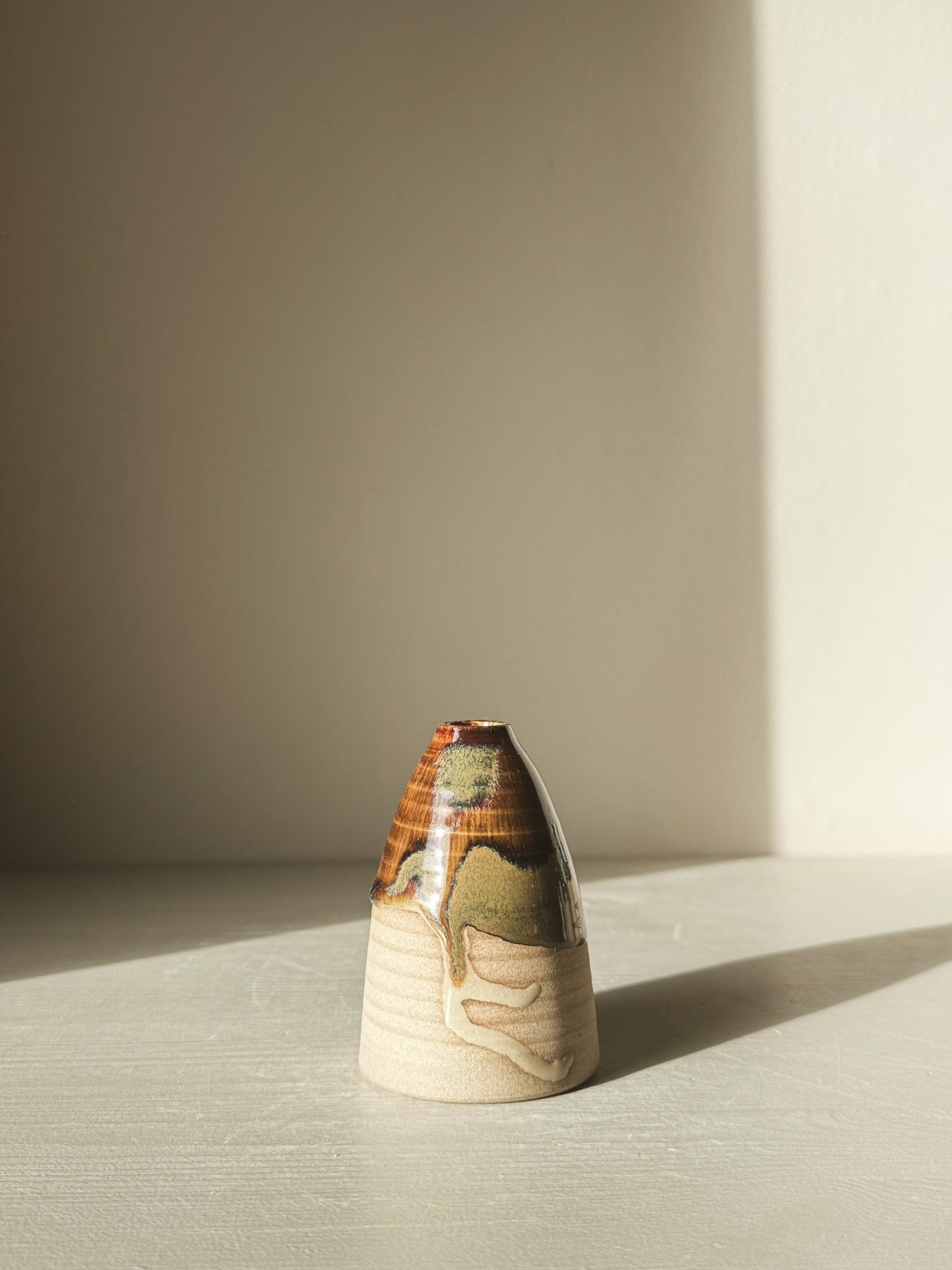 Small Vase – Inyo #02 with glossy tenmoku glaze and raw clay texture, displaying gentle curves and earthy tones in natural light.