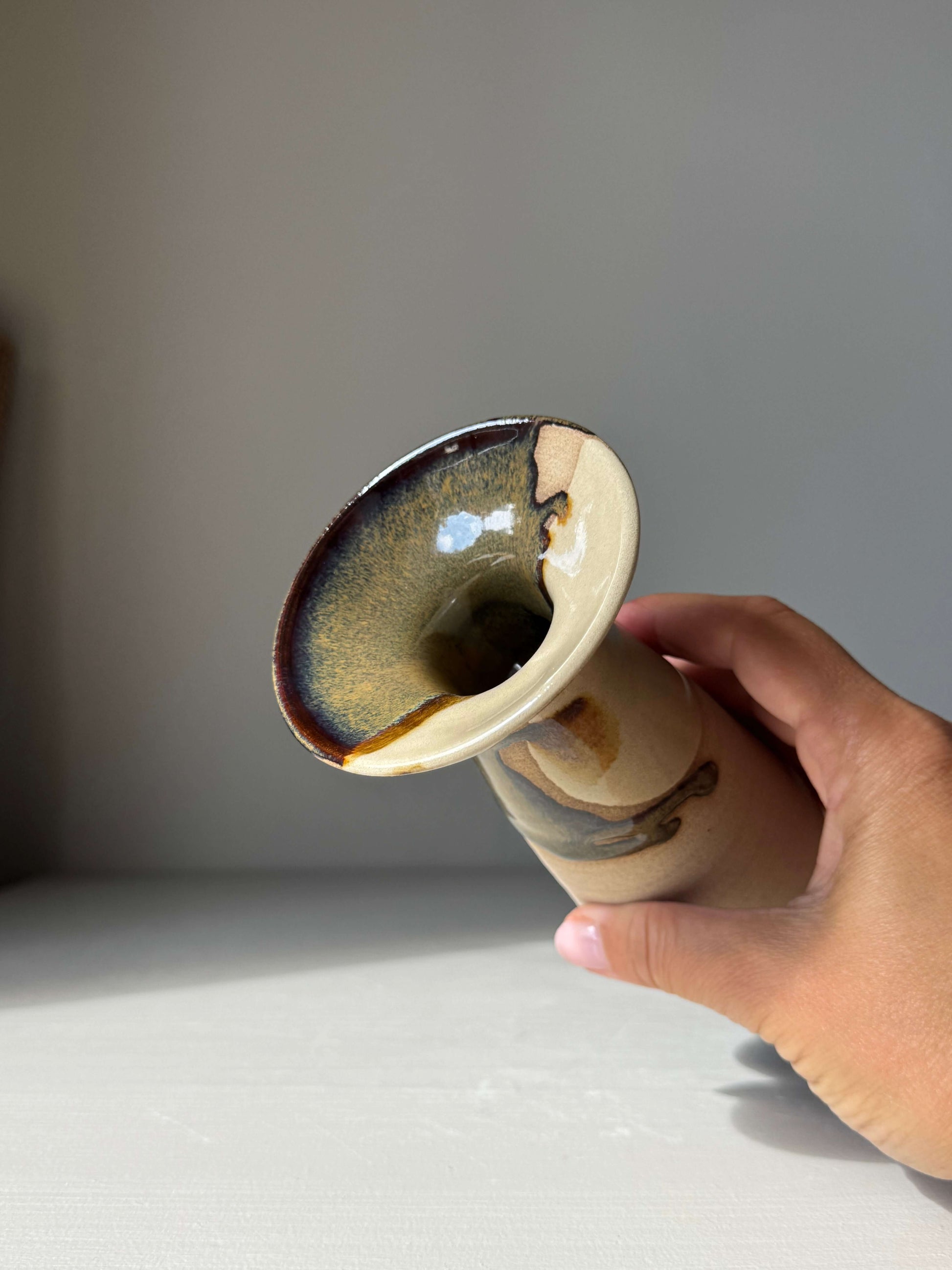 Hand holding Small Vase – Inyo Series #02, a handmade ceramic with unique glazing, showcasing its tall, flared silhouette and tapering waist.