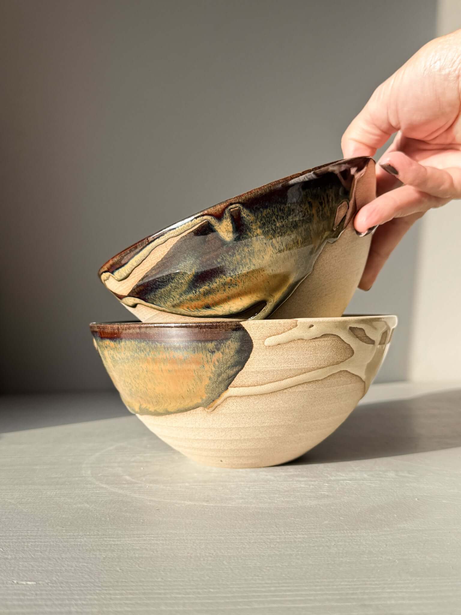 Two handmade ceramic bowls from Soup Bowl – Inyo Series being stacked, showcasing toffee-colored stoneware.