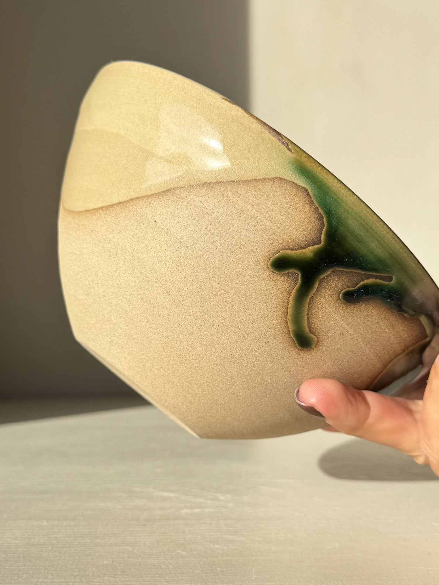 Hand holding a Soup Bowl – Mori Series made of toffee-colored stoneware with green glaze detail.
