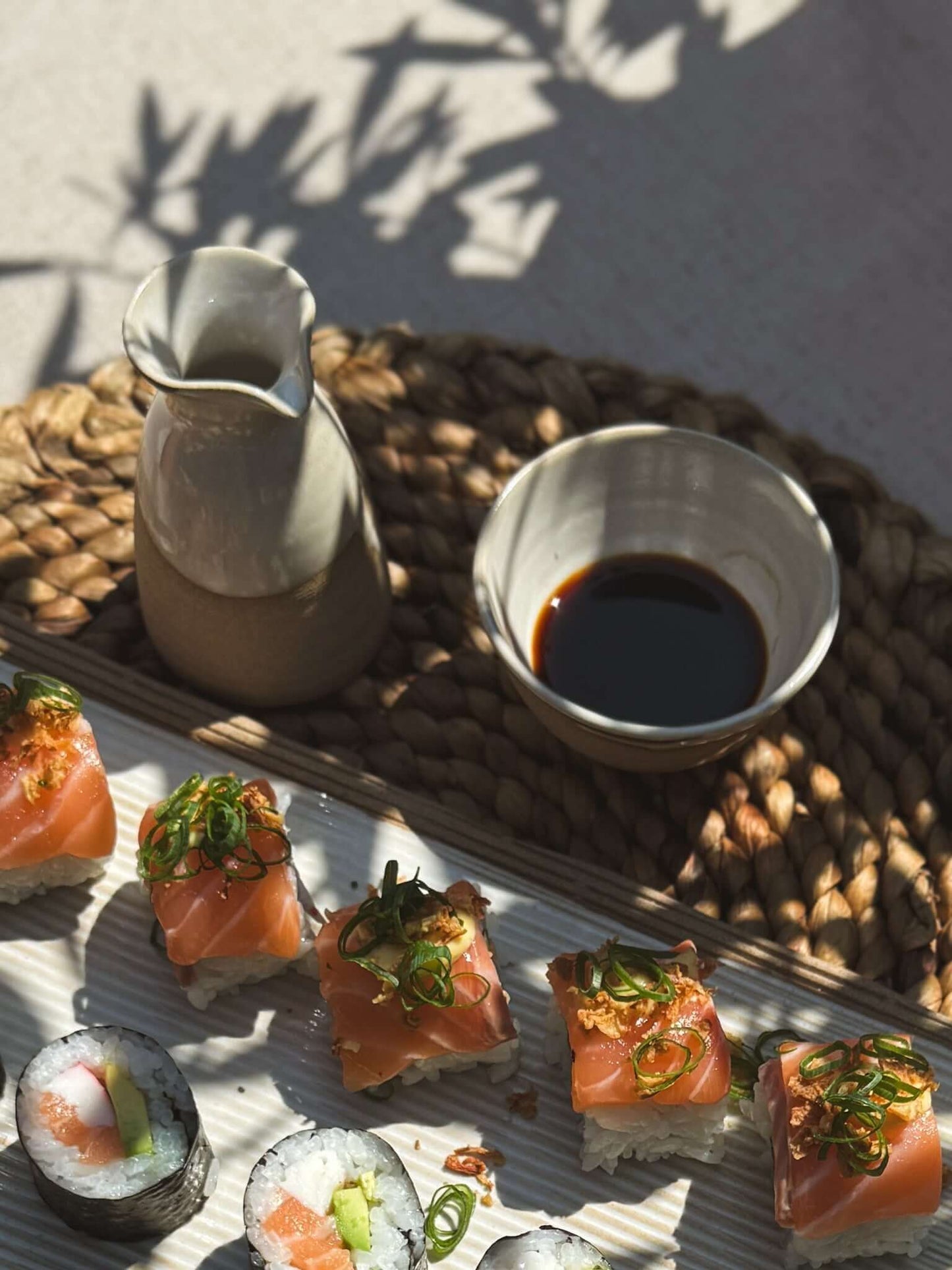 Soya Bowl - Yuki handmade ceramic filled with soy sauce, alongside sushi and a ceramic pitcher on a woven mat.