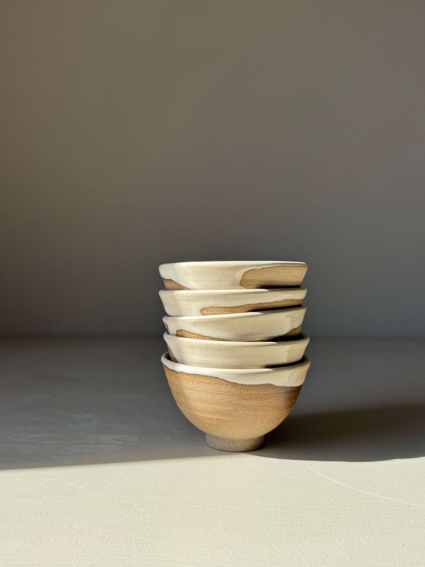 Stack of five handmade ceramic Soya Bowl - Yuki with soft white glaze and raw base on a light background