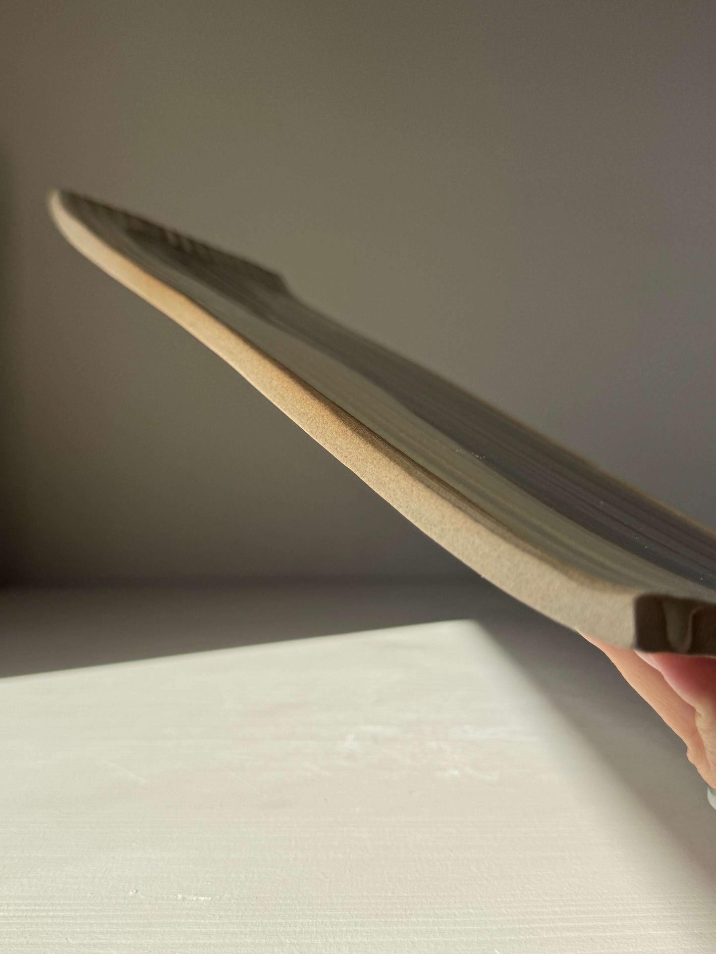 Side view of a handmade ceramic Sushi Plate – Inyo Series #03, showcasing its unique flat form and subtle glaze variations.