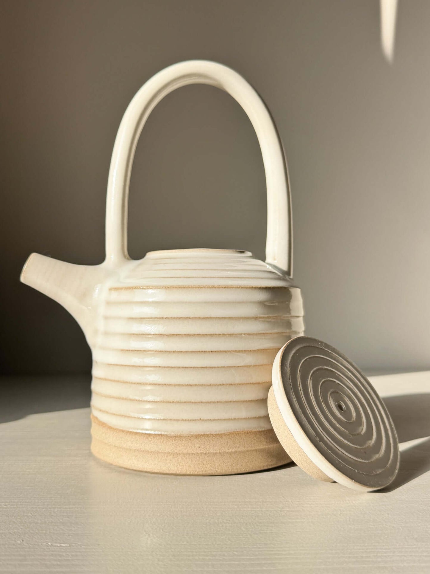 Teapot - Yuki Series #01, handmade ceramic teapot with tall handle and white glaze, showcasing unglazed warm clay base.
