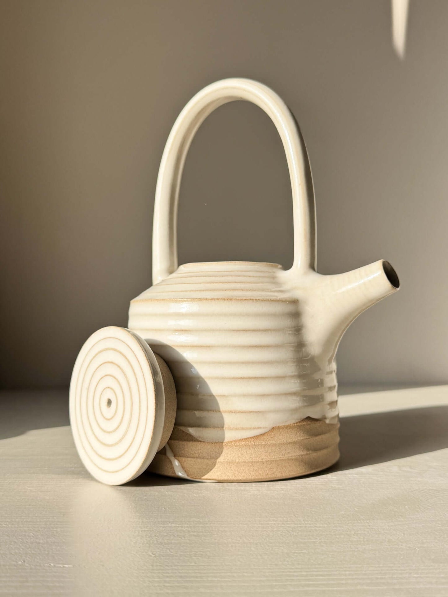 Teapot - Yuki Series #01 with handmade ceramic design, featuring a tall looped handle and white glaze on raw clay base.