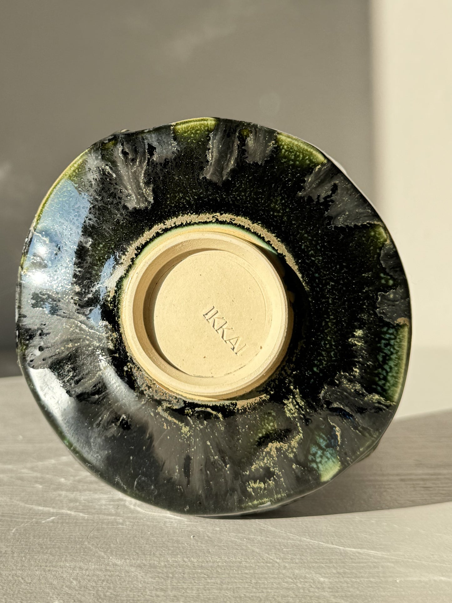 Bottom view of the Textured Matcha Bowl - Hinoki #16 with unique green glaze and textured finish on a light surface.