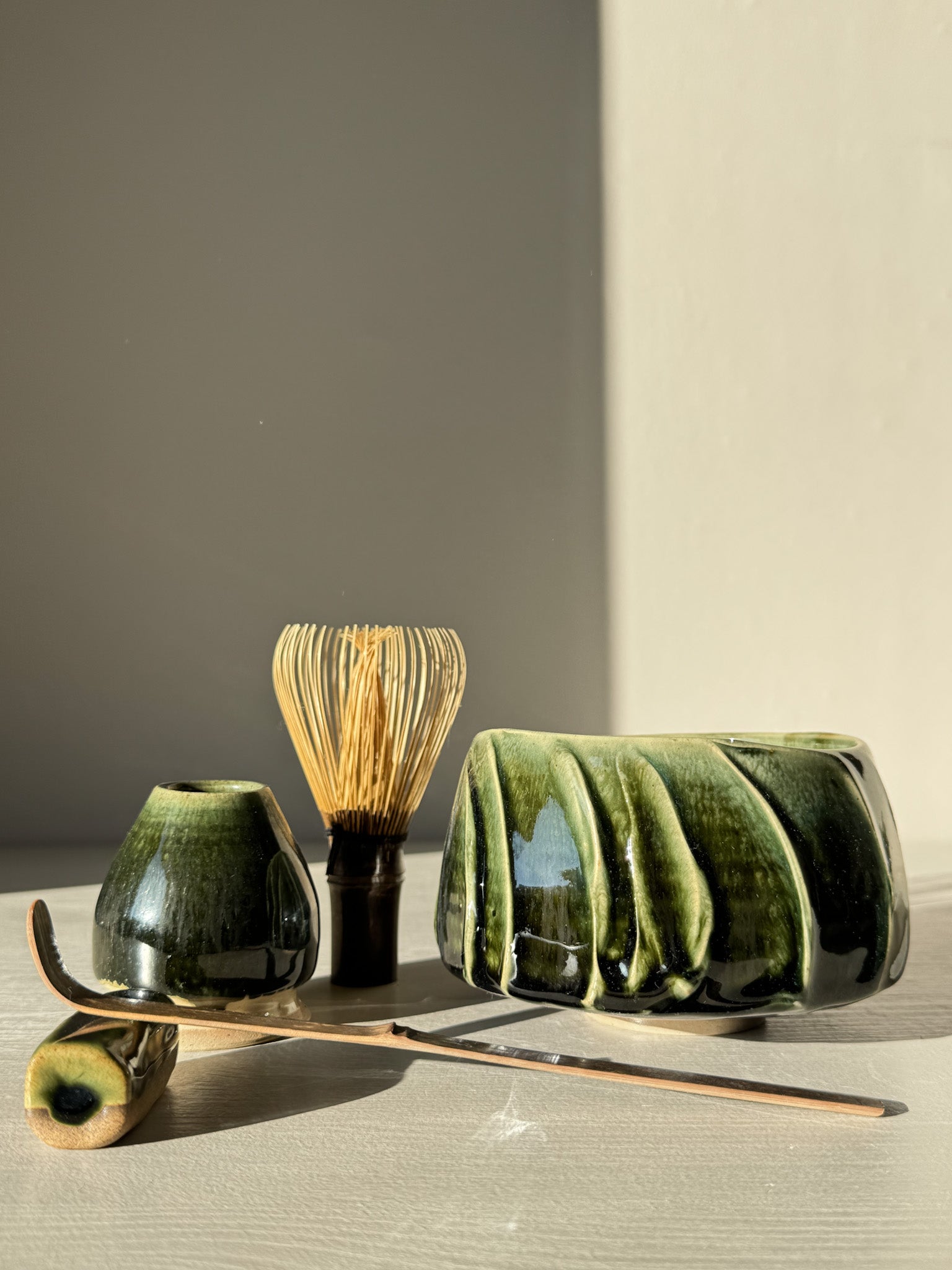 Textured Matcha Bowl - Hinoki #12 with green glaze and bamboo whisk in a serene setting.
